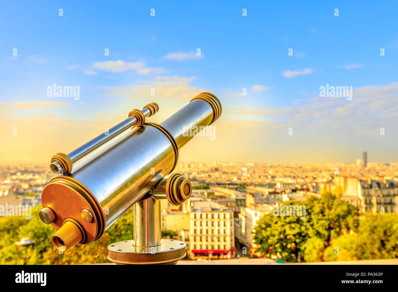 Closeup of look-out binoculars with view above urban cityscape skyline of Paris at sunset light from terrace of Cathedral Sacre Coeur, the highest city point of Paris, Montmartre, France. Copy space. Stock Photo