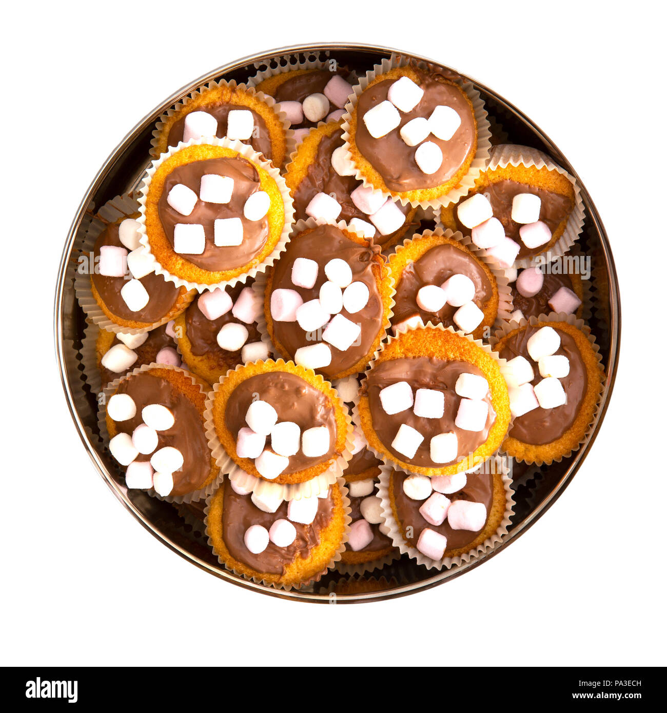 Cake tin full of homemade cup cakes with chocolate and marshmallows on a white background Stock Photo