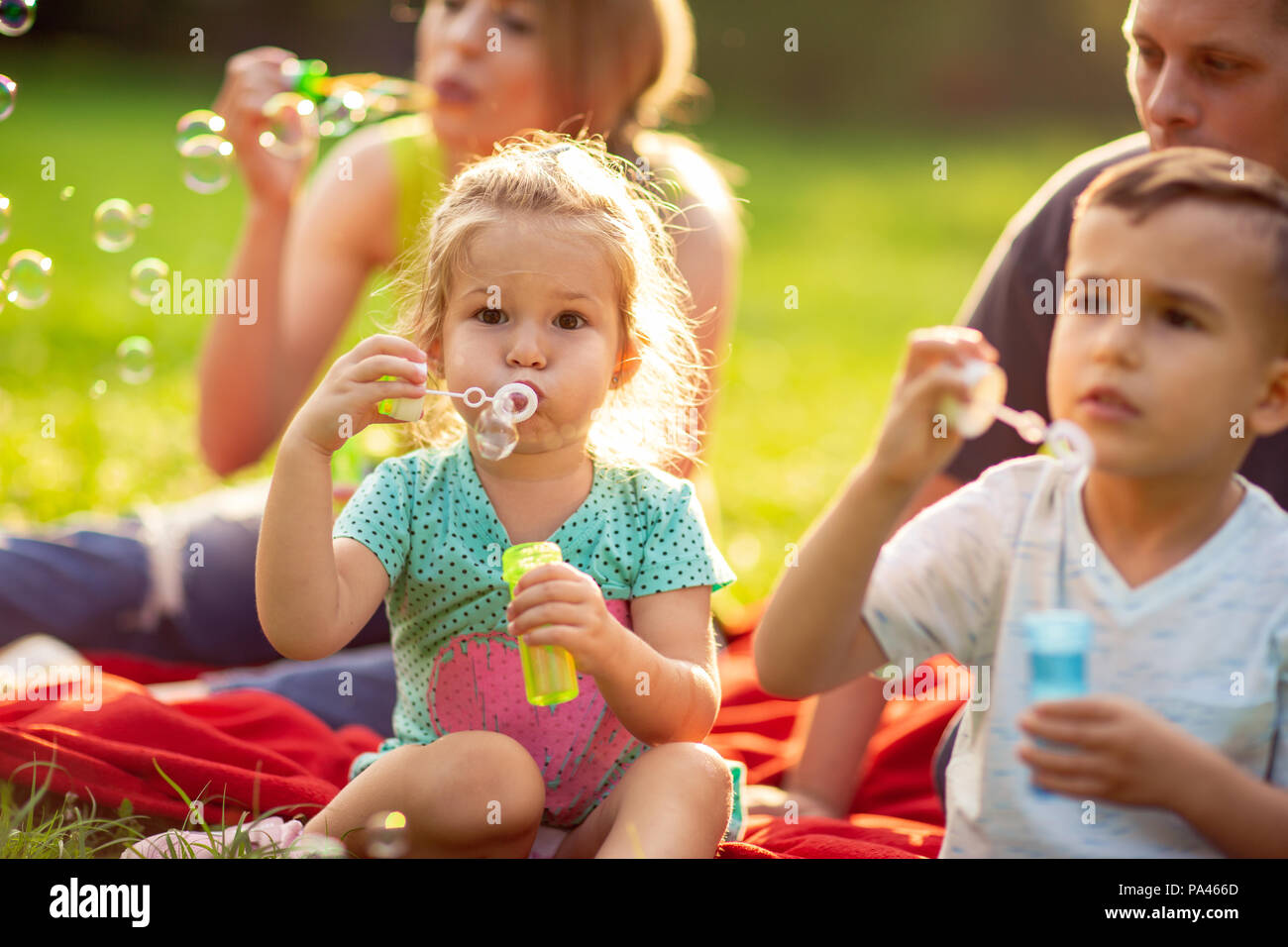 family in the park- cute little girl blows soap bubbles Stock Photo - Alamy