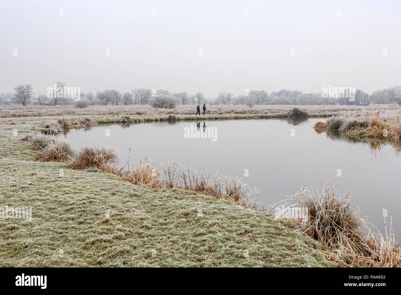 Rural Surrey landscape, southeast England, two people walking on the riverbank of the River Wey