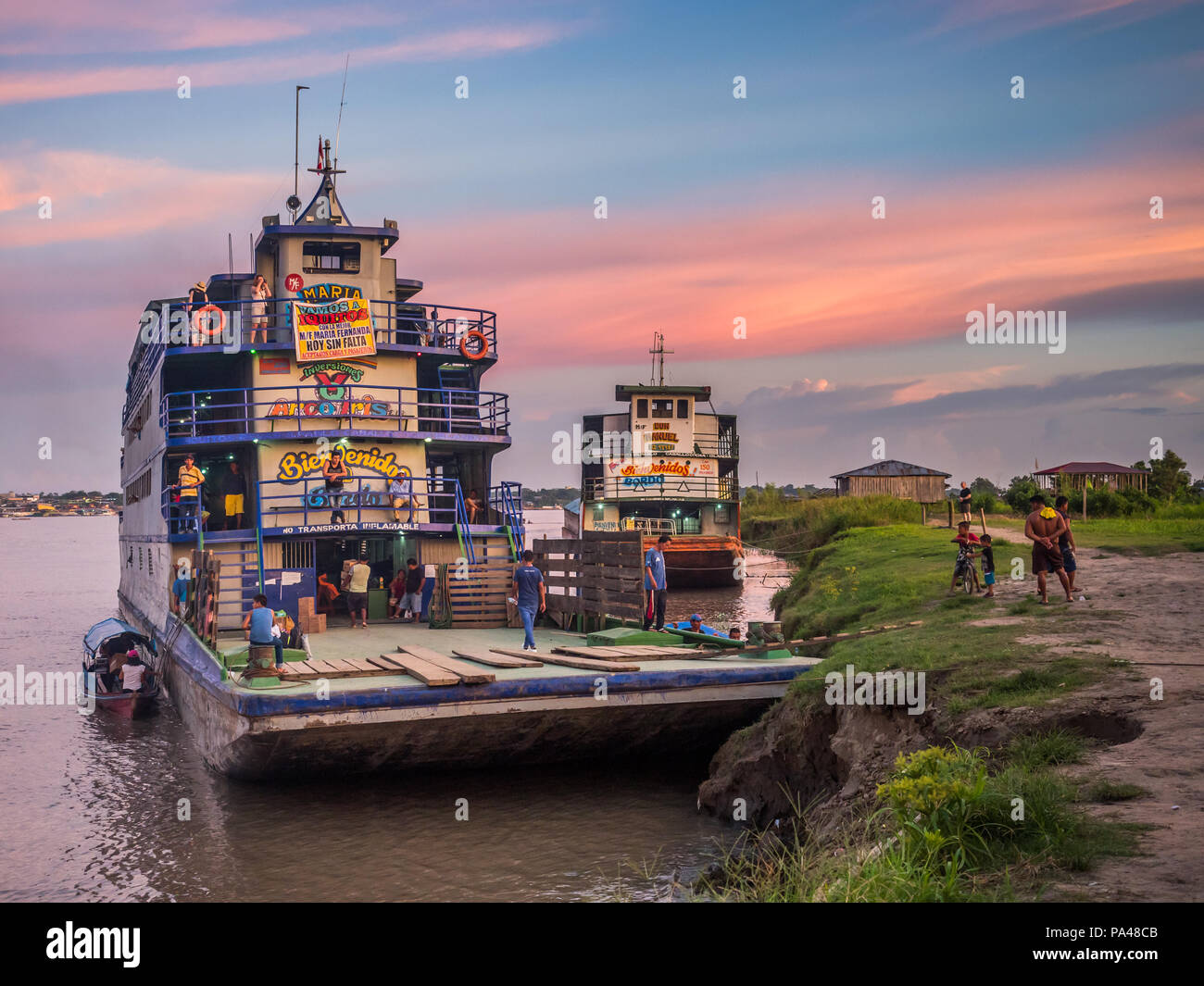 Santa Rosa, Peru - Mar 24, 2018: Sunset over the Amazon river and the cargo boat waiting at the port. Stock Photo