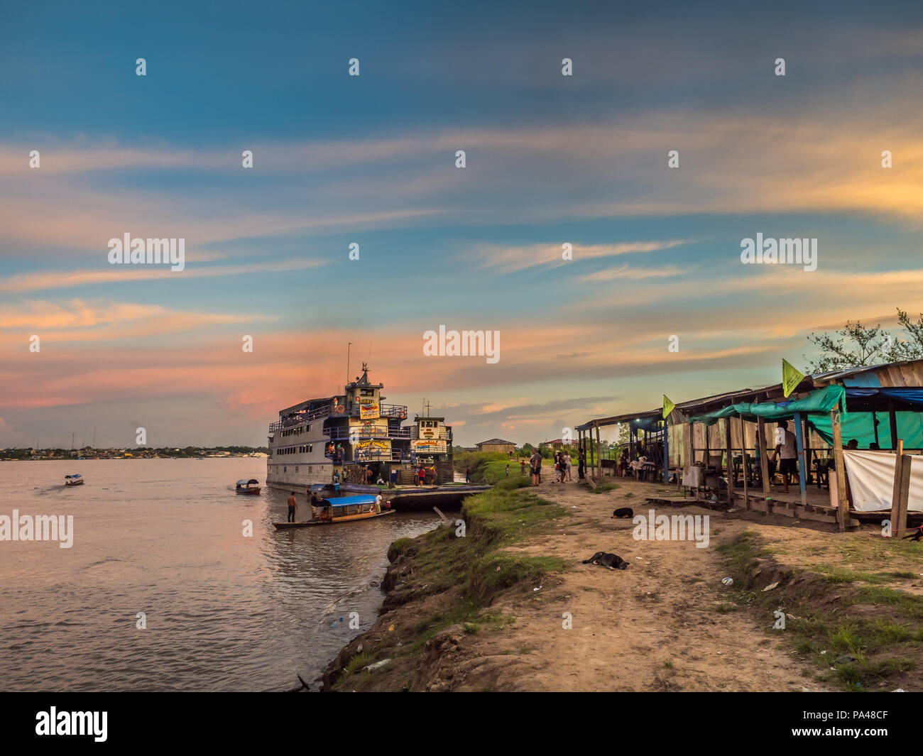 Santa Rosa, Peru - Mar 24, 2018: Sunset over the Amazon river and the cargo boat waiting at the port. Stock Photo