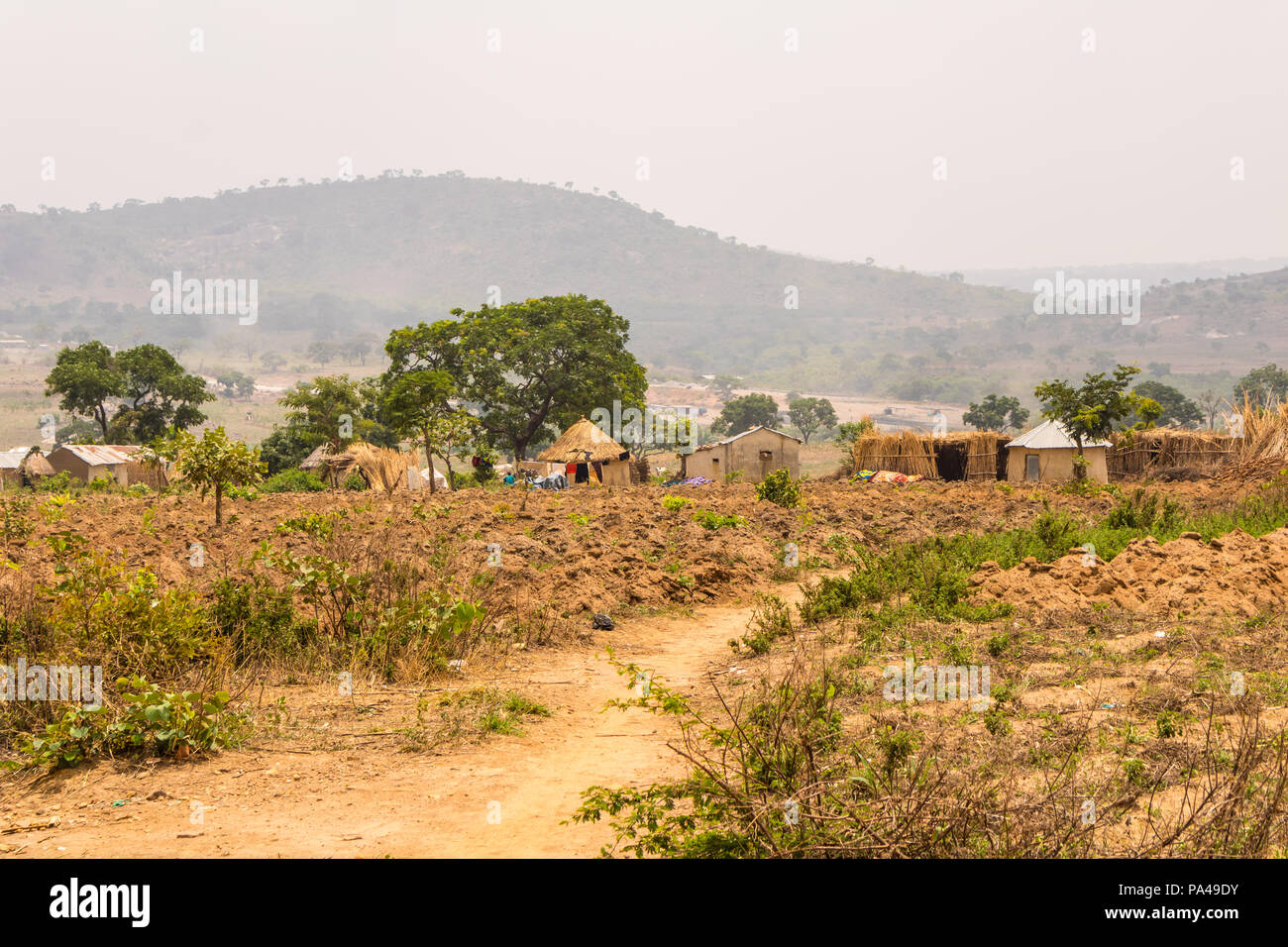 A farm settlement in the remote rainforest of Africa with a view of huts, mountain and the sky. Stock Photo