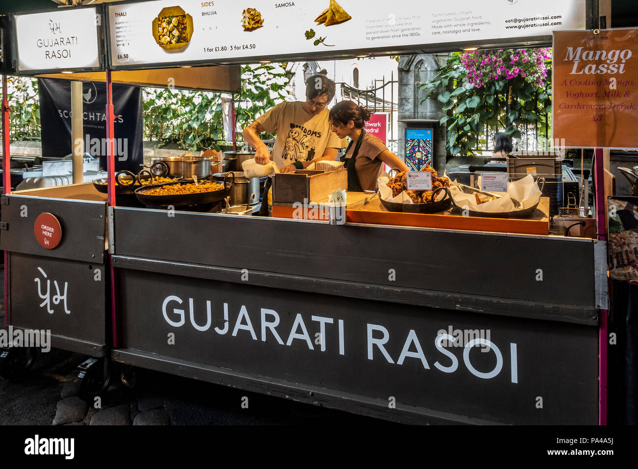 Two workers at the Gujarati Rasoi Indian Street Food stall preparing for service at famous and historic Borough Market, Southwark, London, UK Stock Photo
