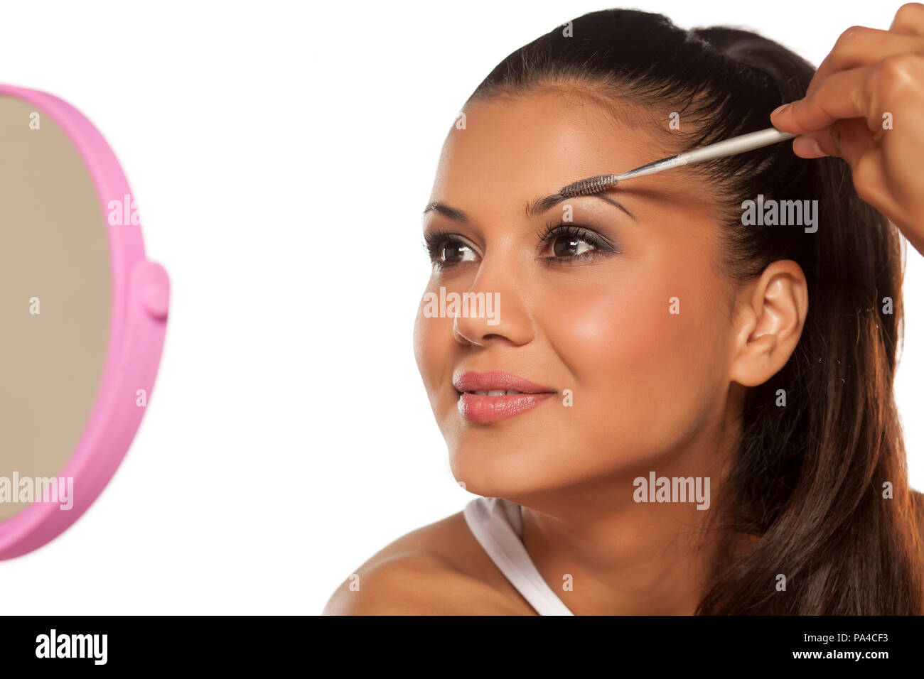 A young Indian woman shaping her eyebrows with a brush Stock Photo