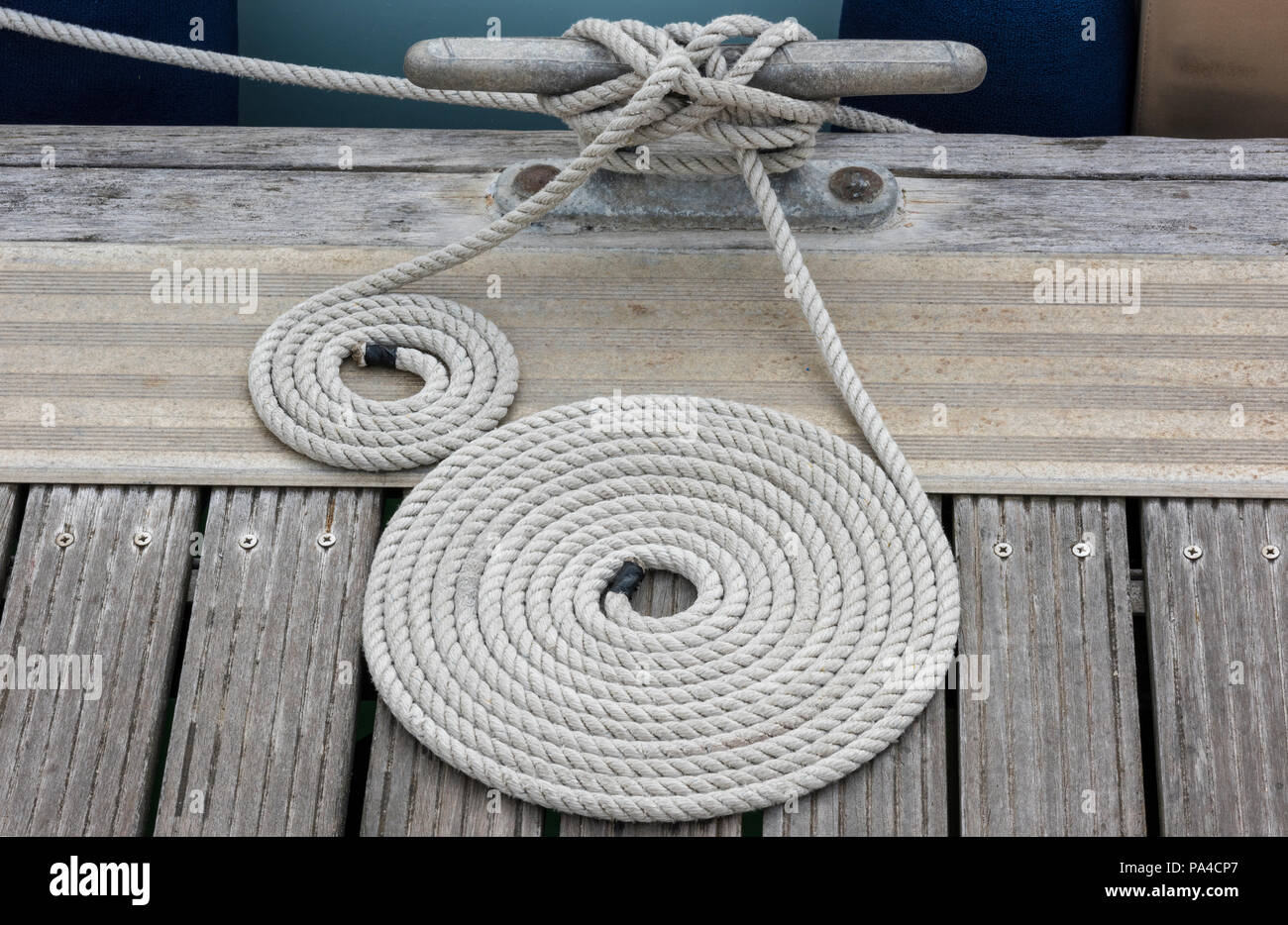 a neatly coiled yacht mooring rope on a wooden jetty. a rope made into a cheese for tidiness. Stock Photo