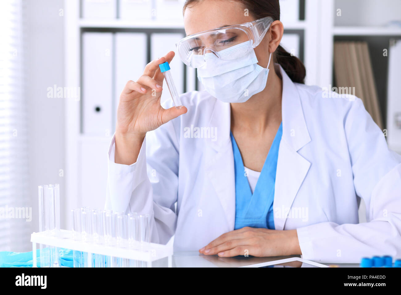 Female scientific research is looking at the tube in laboratory. Blood