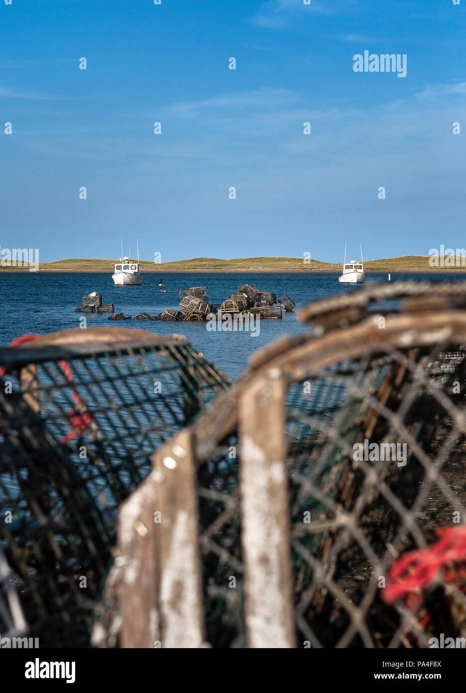 Wooden lobster traps and boat in Nauset Harbor, Orleans, Cape Cod, Massachusetts, USA. Stock Photo