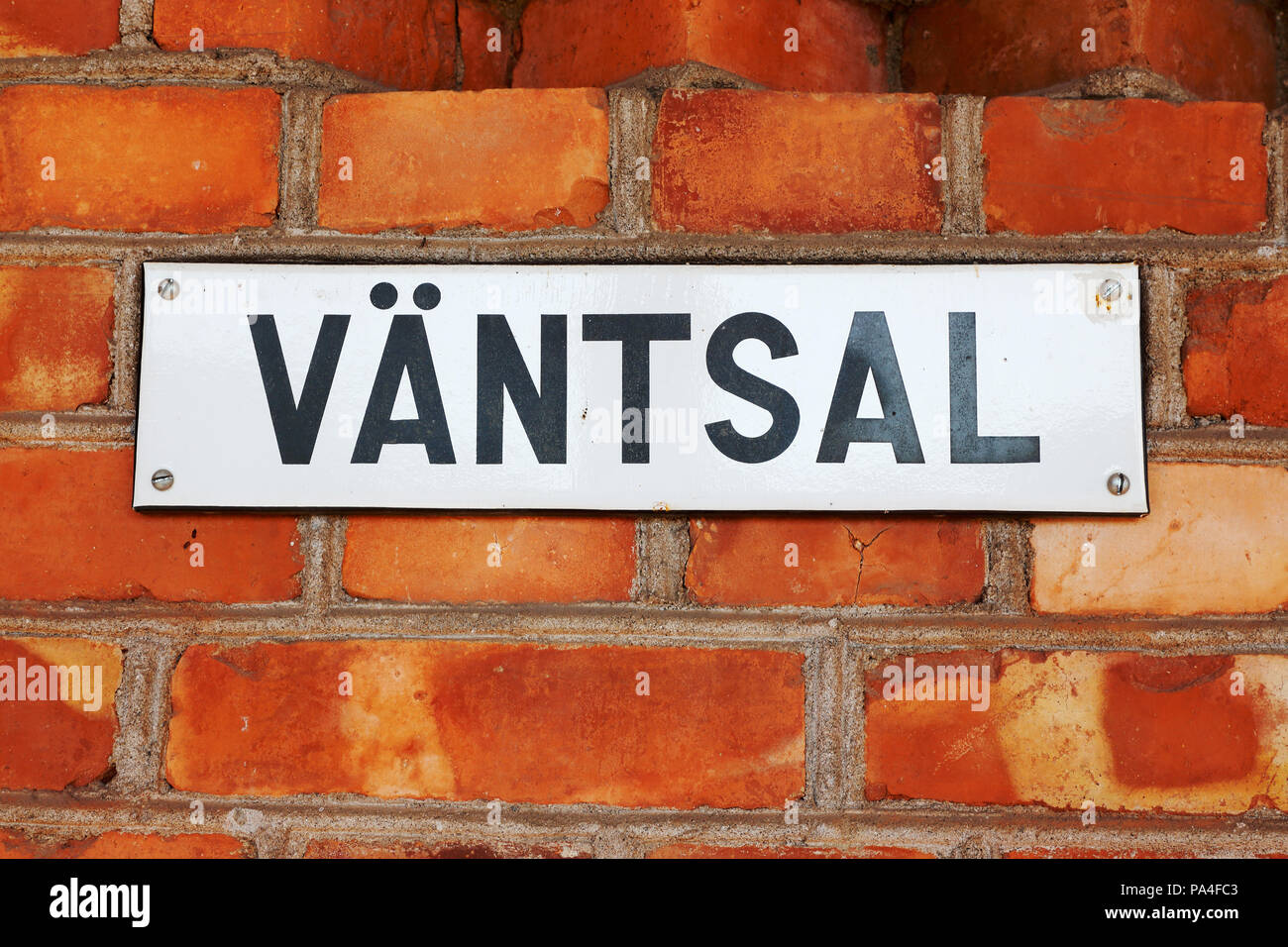 Sign with the Swedish word for waitning hall on a red brick wall. Stock Photo