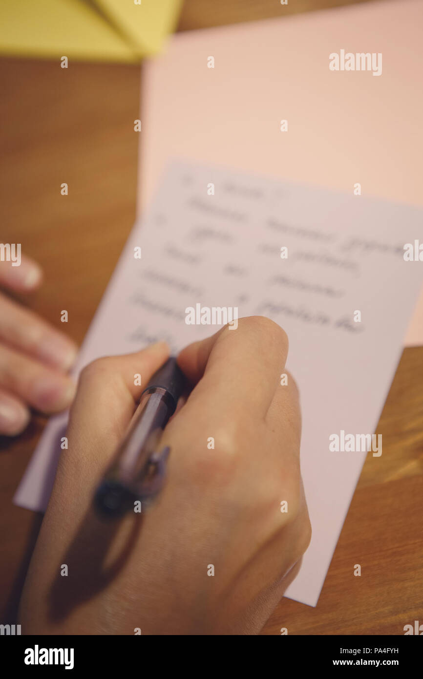 Closeup of a human female hand holding pen and writing letter or text on paper on the background, selective focus, shallow depth of field, toned with  Stock Photo