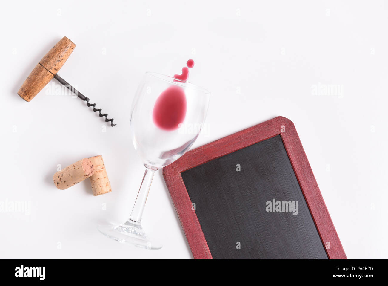 Blank Wine Menu: Chalkboard with wine glass, corkscrew, corks, and wine spill on white with copy space. Stock Photo