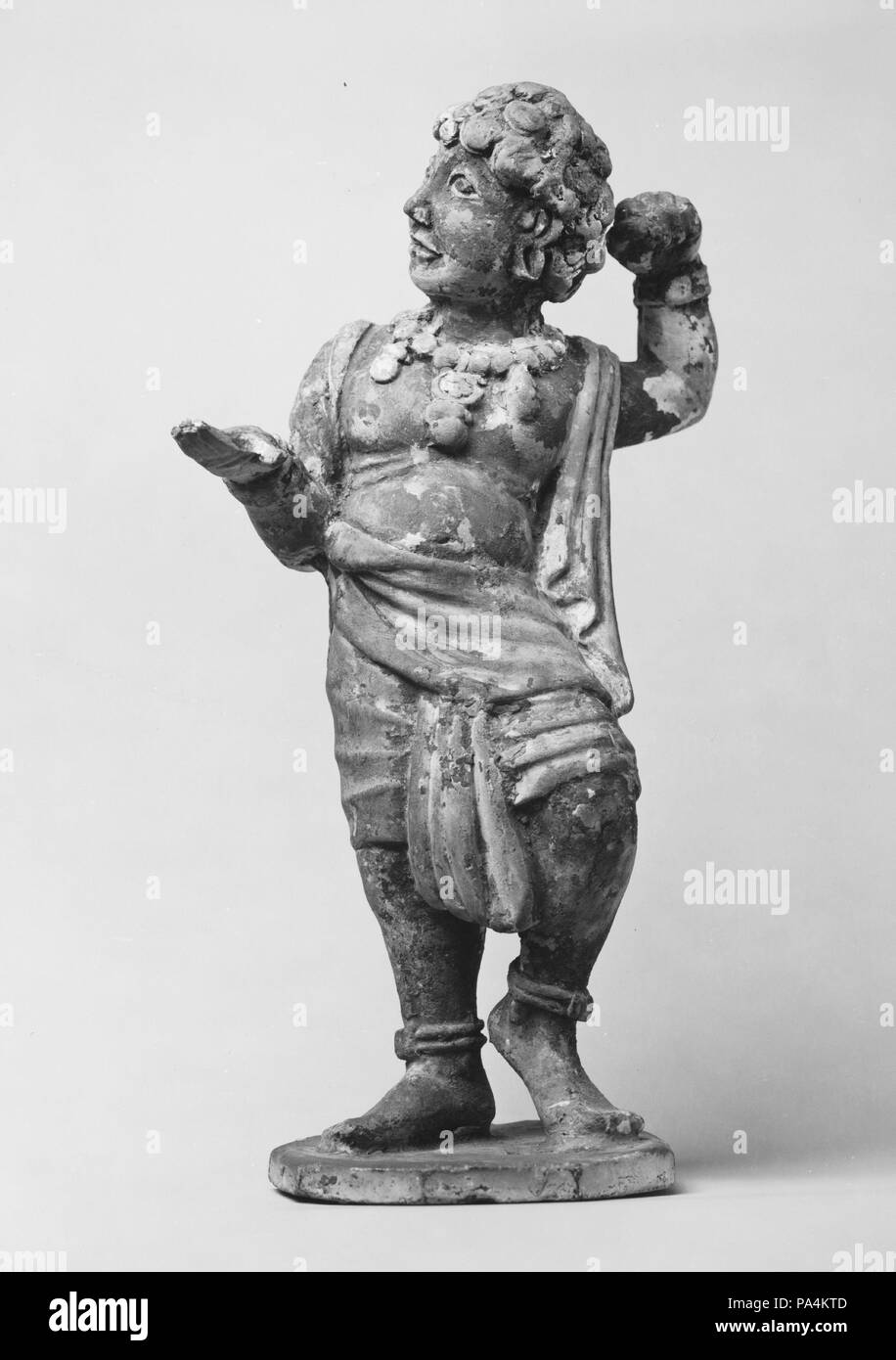 Figure of a Foreign Dancer. Culture: China. Dimensions: H. 10 1/2 in. (26.7 cm). Date: 7th century.  Representations of foreigners are frequently found among Tang pottery sculptures, illustrating the cosmopolitan culture of the period. This figure can be identified by his dark skin, prominent eyes, curly hair, and scanty clothing as a dancer from South or Southeast Asia. Museum: Metropolitan Museum of Art, New York, USA. Stock Photo