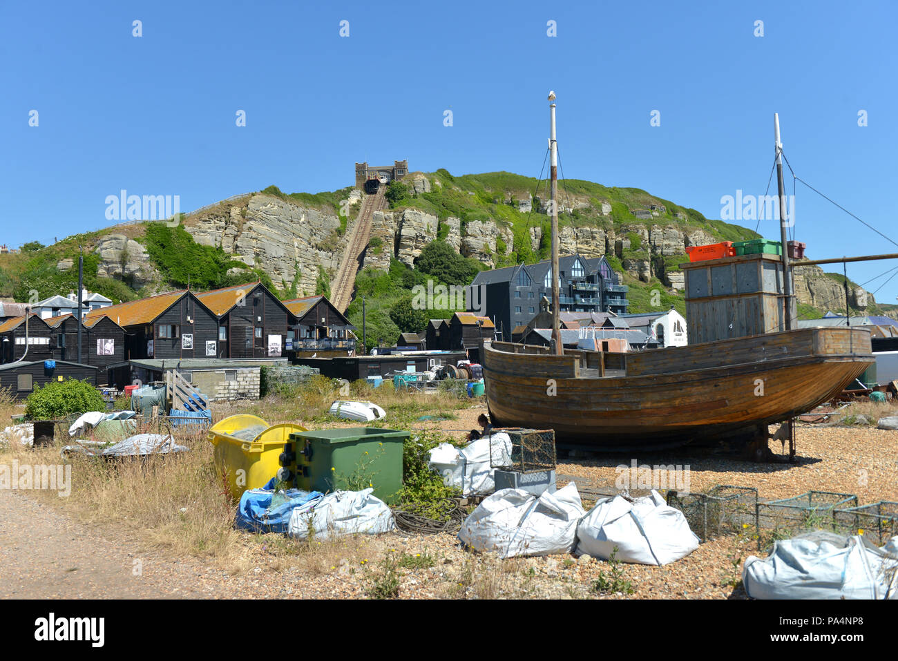 Fishing boats and net huts on the Stade, Hastings Old Town beach, with East Hill Cliff railway. Stock Photo