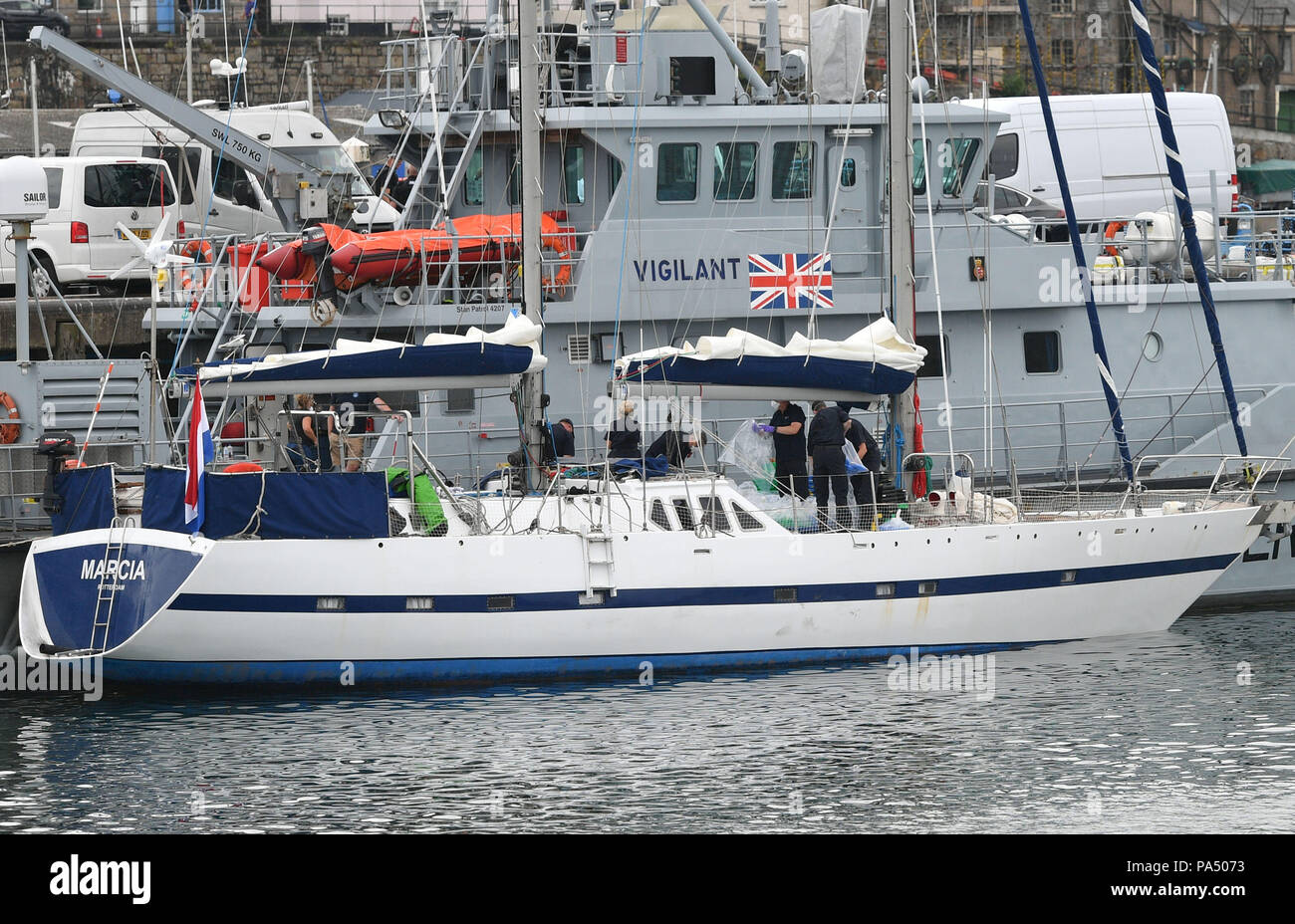 Drugs are unloaded from a boat by officers at Newlyn harbour, with the Border Force cutter HMC Vigilant behind, after the National Crime Agency seized a sailing yacht in the English Channel and bought it back to the harbour and arrested two men on suspicion of drug trafficking. Stock Photo