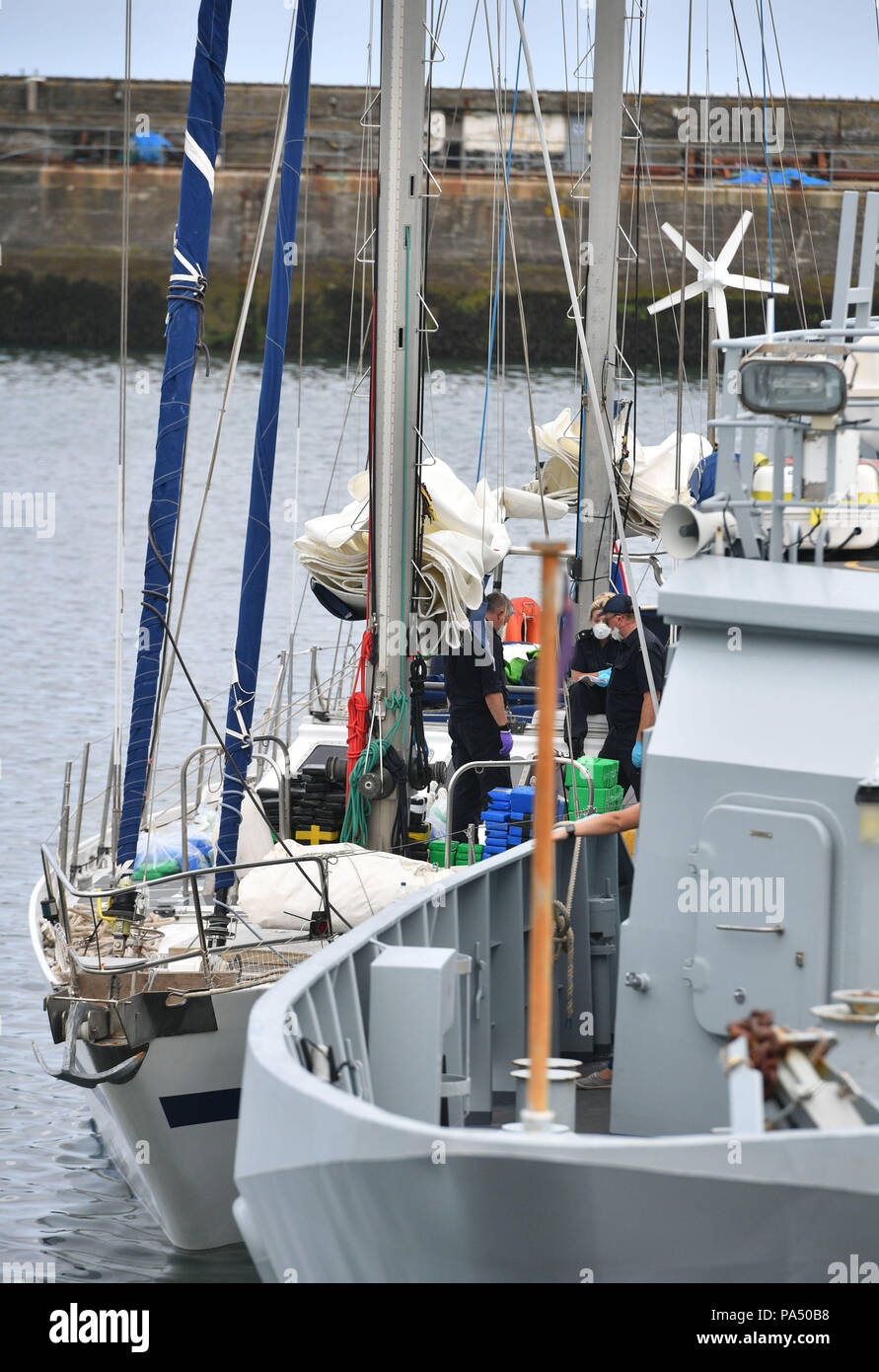 Drugs are unloaded from a boat by officers at Newlyn harbour, with the Border Force cutter HMC Vigilant (right), after the National Crime Agency seized a sailing yacht in the English Channel and bought it back to the harbour and arrested two men on suspicion of drug trafficking. Stock Photo
