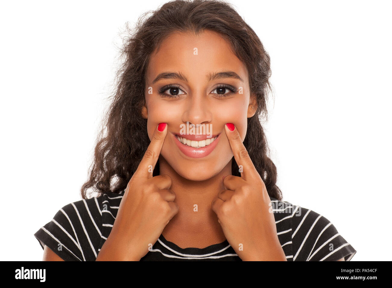 beautiful young dark skinned woman forsed her smile with her fingers Stock Photo