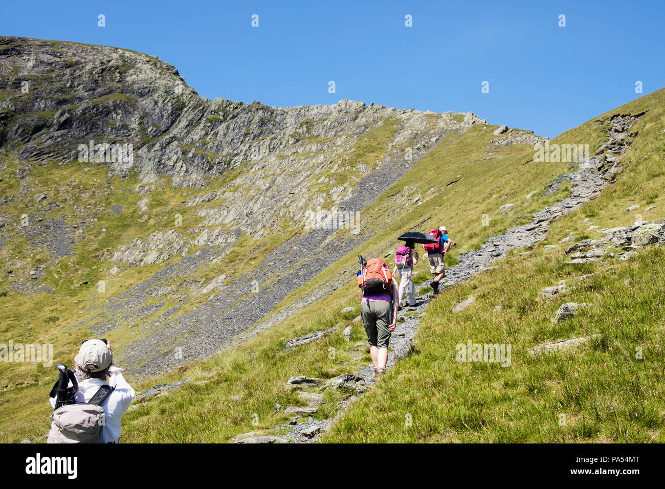 Hikers hiking on a mountain path to Sharp Edge on Blencathra (Saddleback) in mountains of Lake District National Park. Keswick, Cumbria, England, UK Stock Photo