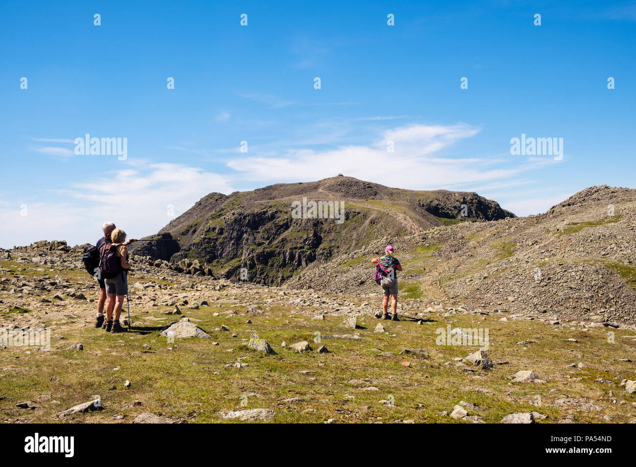 Hikers on path over Ill Crag and Broad Crag to Scafell Pike summit in mountains of Lake District National Park, Cumbria, England, UK, Britain Stock Photo