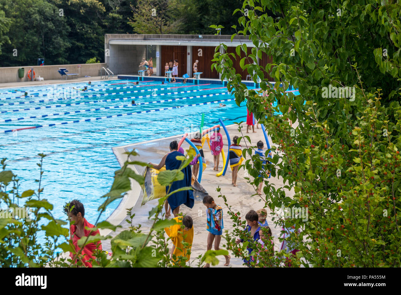 Children carrying floats, tubes, foam noodles are a swimming camp, outdoor swimming pool