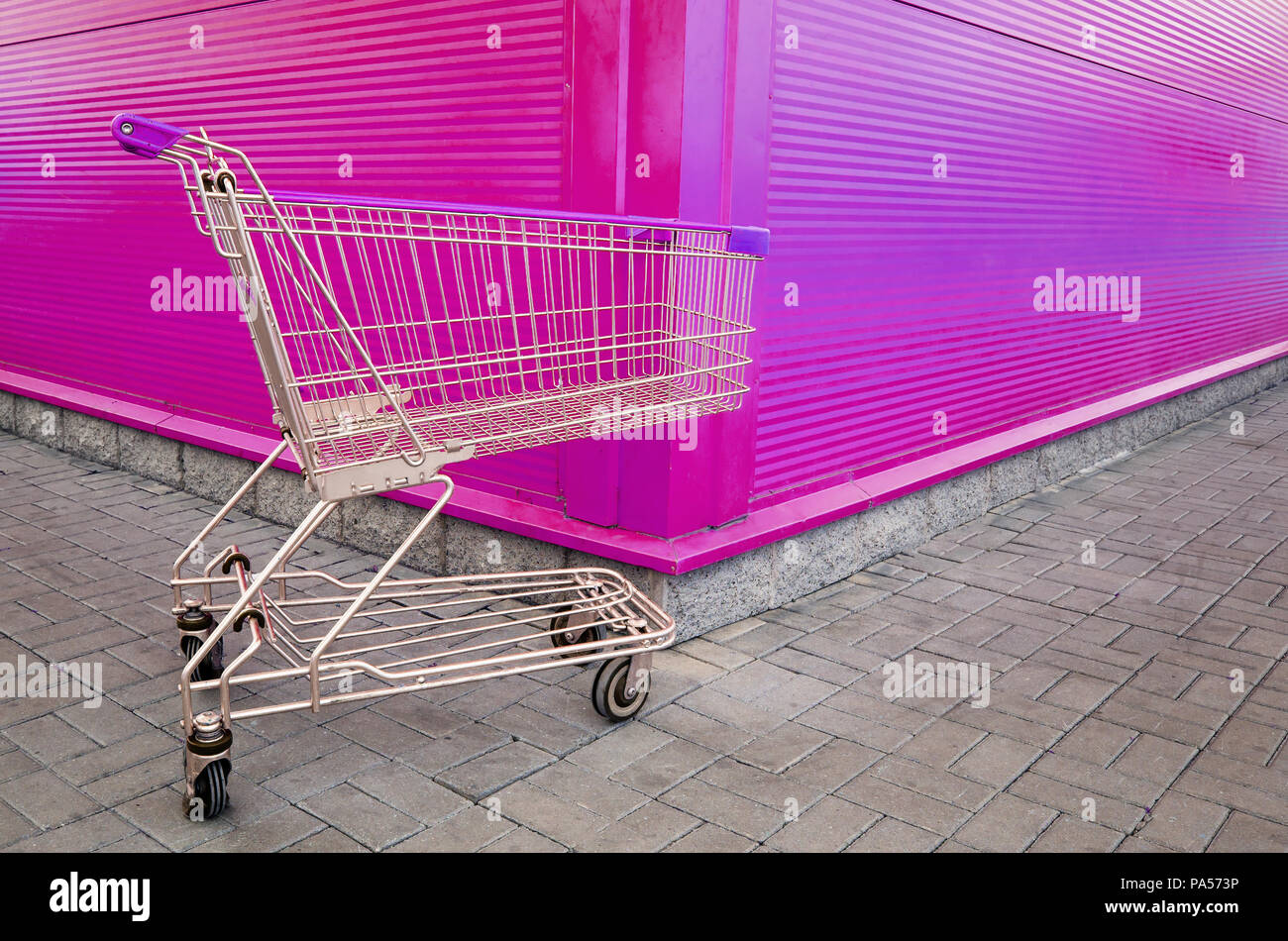 Empty shopping cart parking on violet or pink background with copyspace. retail store. Stock Photo