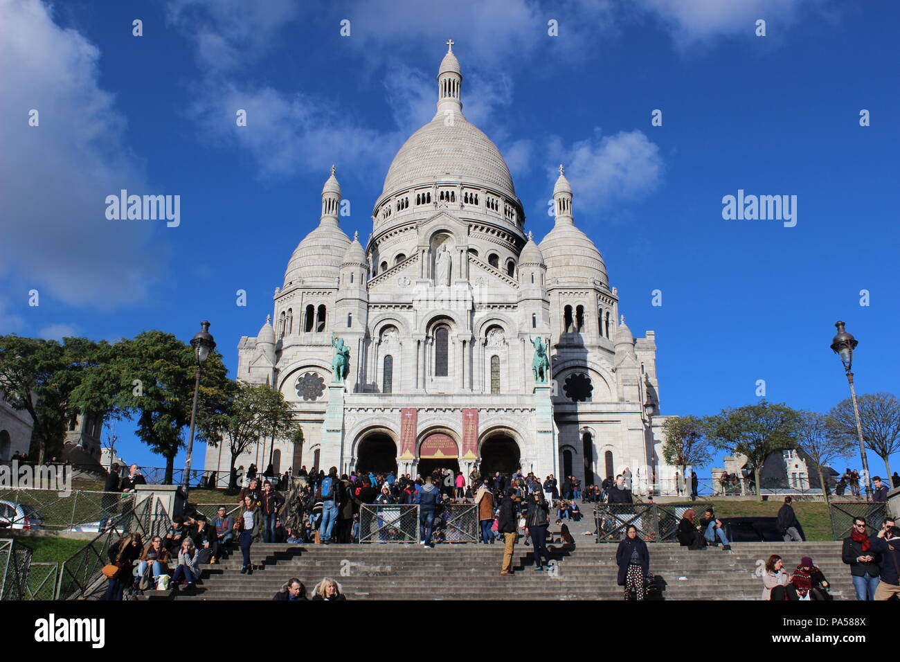 Lots of tourists come to see this beautiful Sacre Coeur Basilica and taking photos, having rest and enjoying mesmerizing view of Paris. Stock Photo
