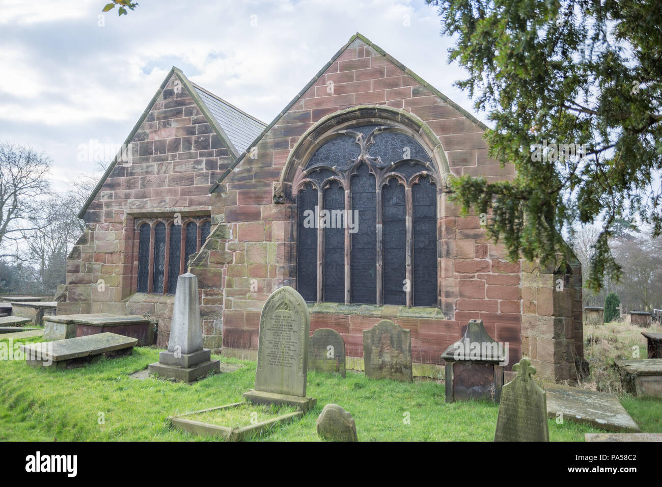 Church building with grave stones, head stones and a yew tree Stock Photo