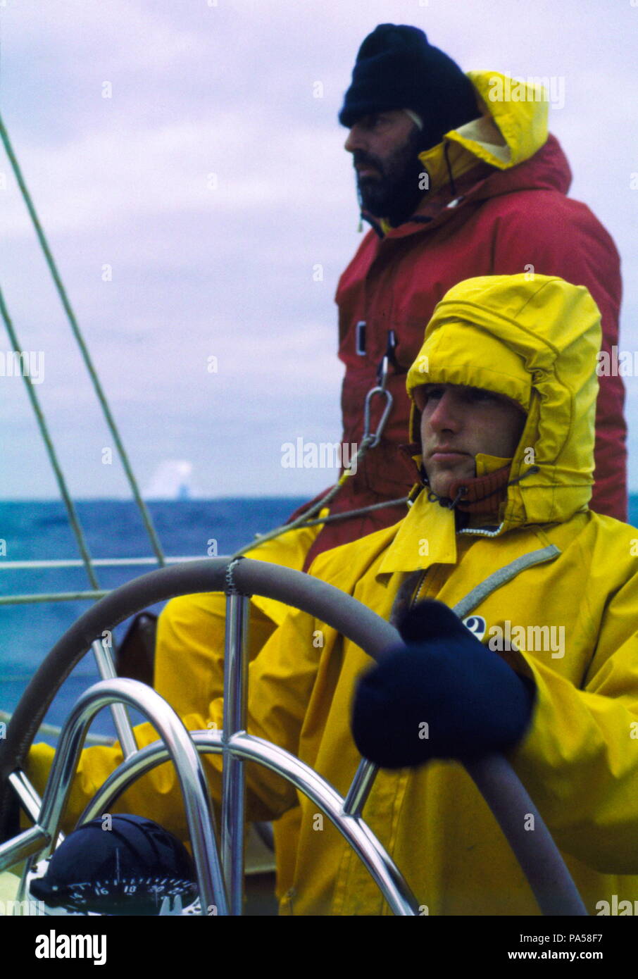 AJAXNETPHOTO. 1978. SOUTHERN OCEAN. - WHITBREAD RACE - ICEBERG COUNTRY - JULIAN GILDERSLEEVES STEERS CONDOR (GBR) THROUGH TREACHEROUS ICEBERG WATERS OF THE SOUTHERN OCEAN WHILE CO-SKIPPER LES WILLIAMS KEEPS A SHARP LOOKOUT. PHOTO:GRAHAM CARPENTER/AJAX REF:804582 Stock Photo