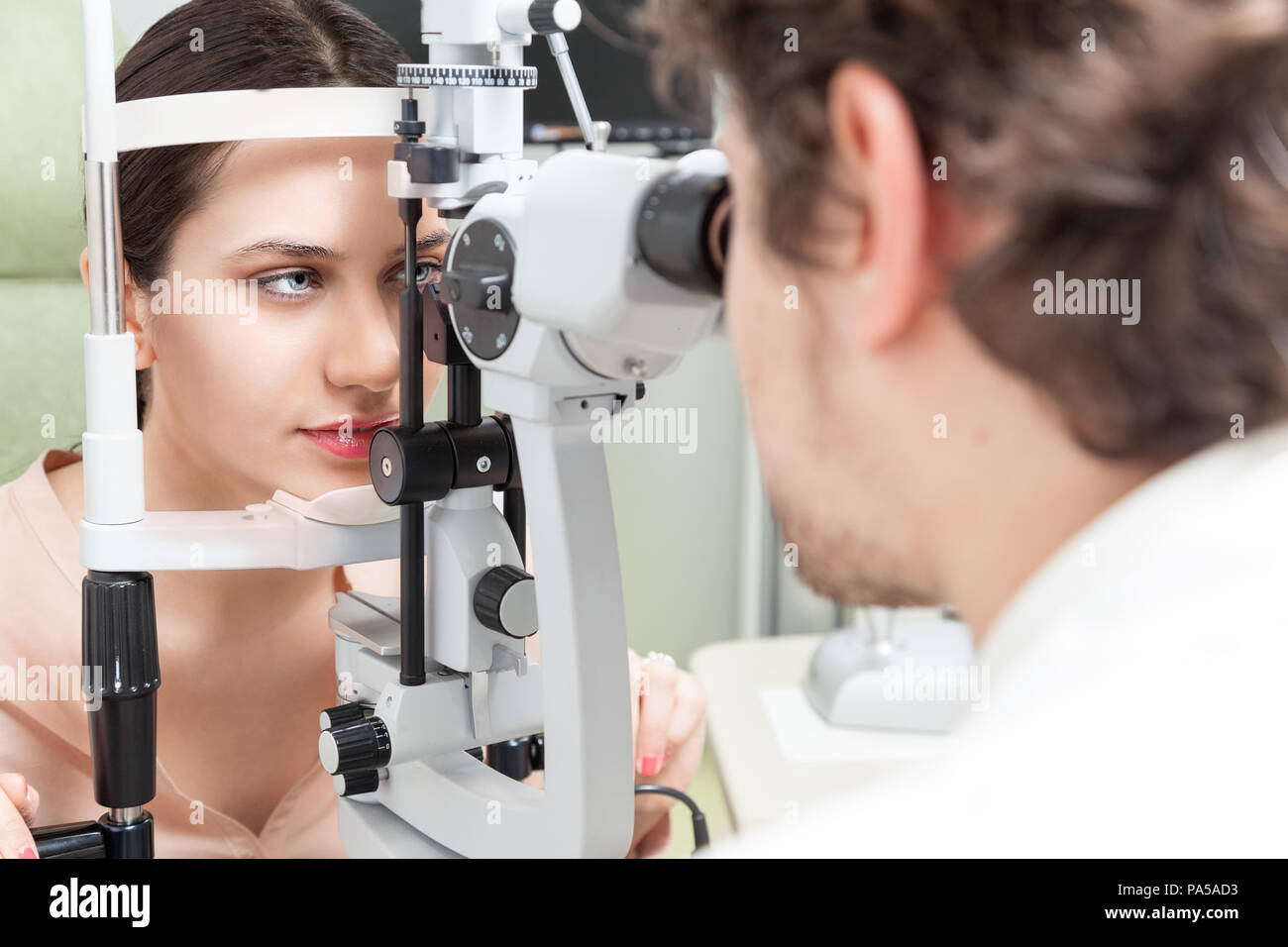 Pretty woman during an exam with Slit Lamp / the ophthalmologist in eyes clinic doing cornea and retina exam diagnostic / high technology concept eyes Stock Photo