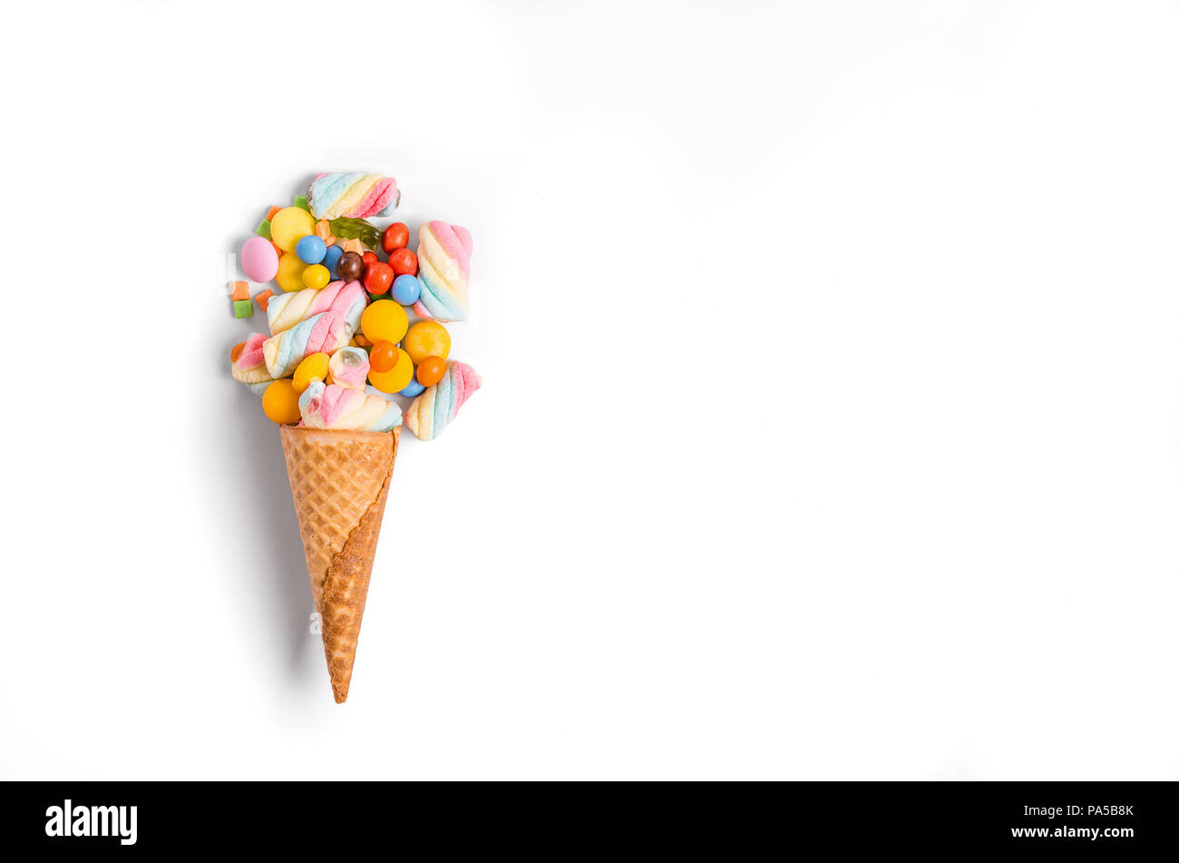 Ice cream cone flat lay image with colorful candy packing into the cone. Stock Photo