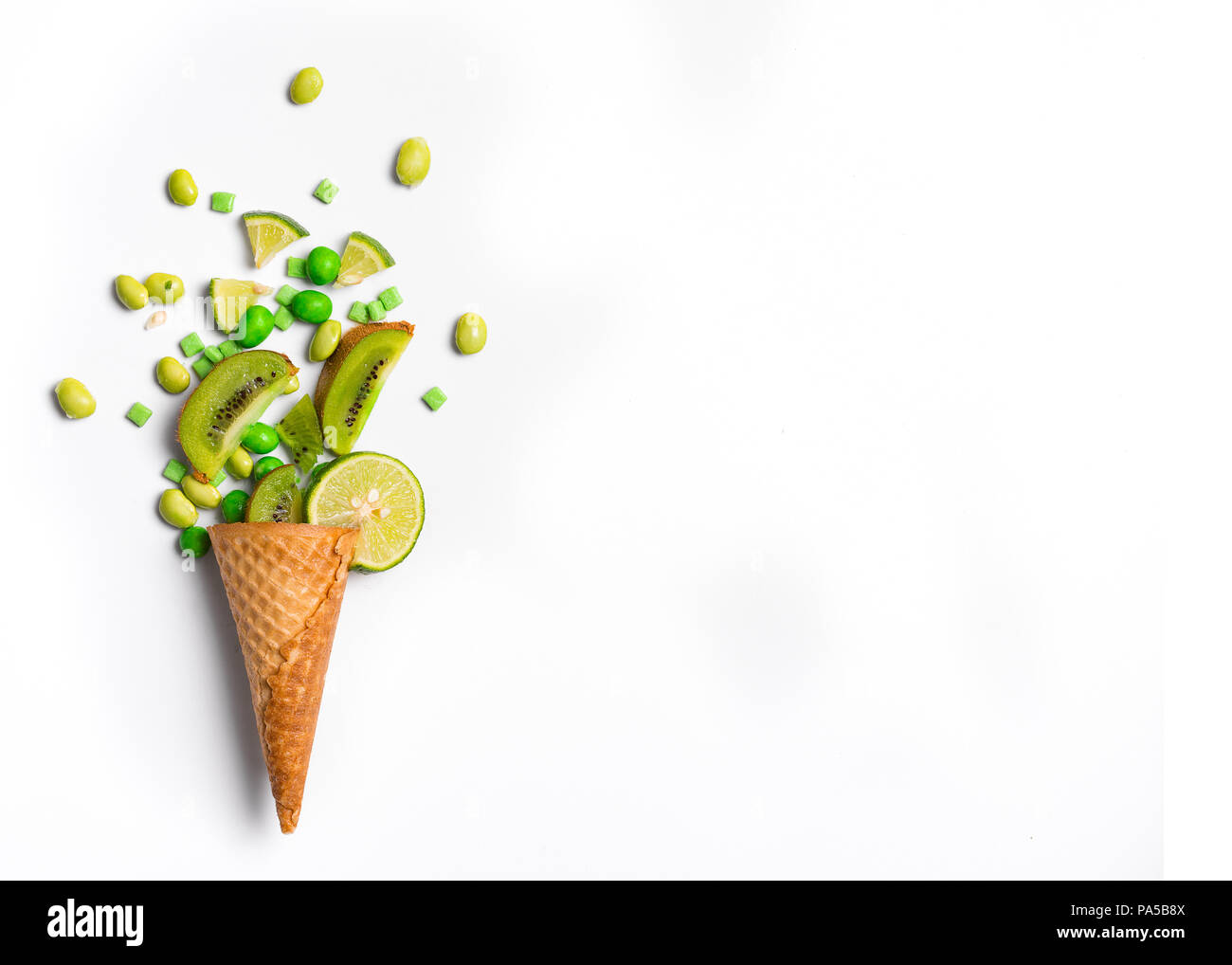 Ice cream cone flat lay image with green candy and kiwifruit packing into the cone. Stock Photo