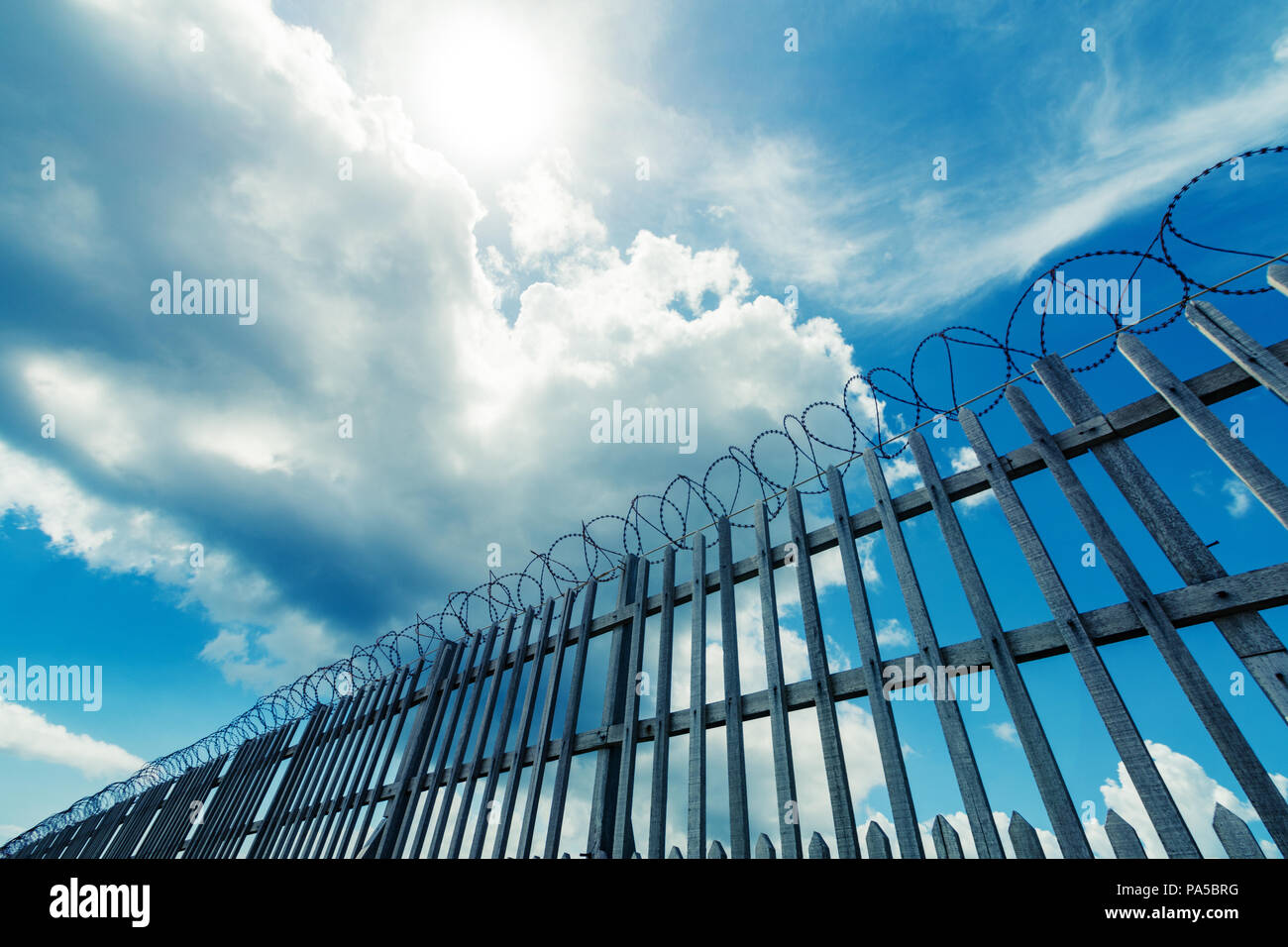 Barbed wire fence surrounding a prison , military or other high ...