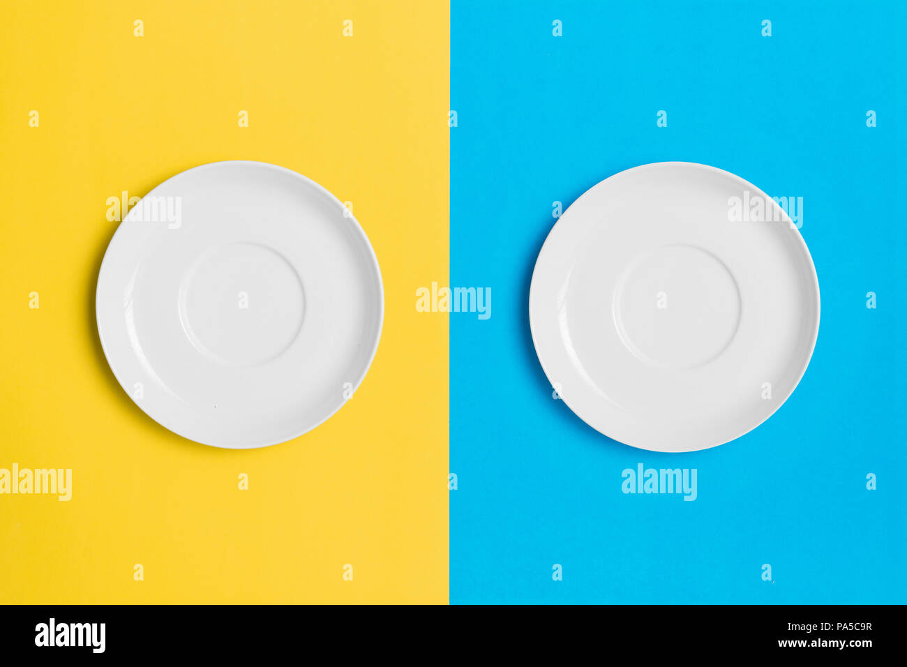 Empty plates on a contrasting yellow and blue background. Stock Photo
