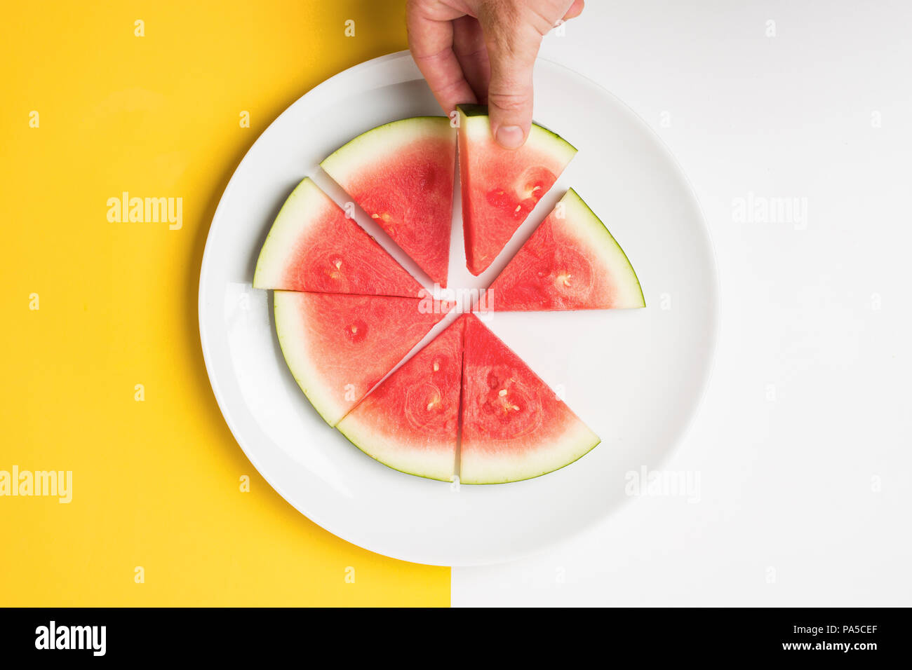Hand holding slice of watermelon over split color background. Stock Photo