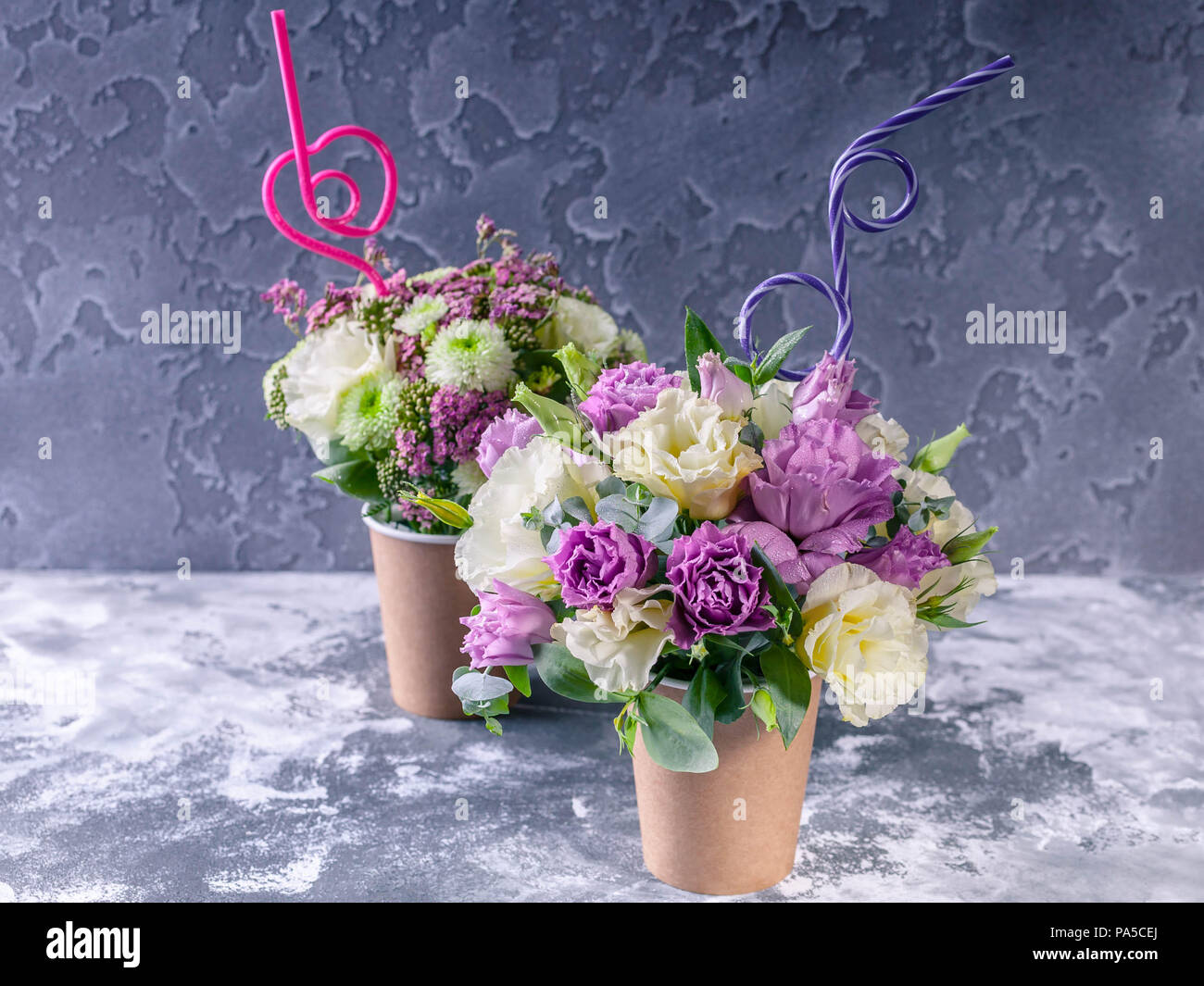 Bouquets of flowers in a coffee cup on a concrete background. Flower compliment Stock Photo