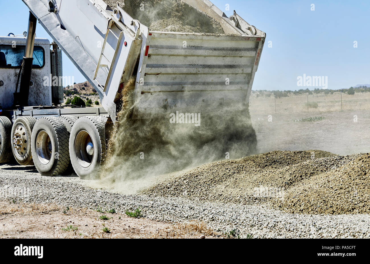 A dump truck spreading gravel on a dirt driveway Stock Photo - Alamy