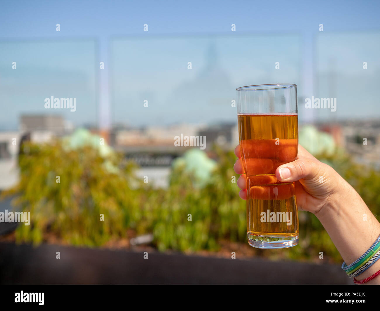 Womans hand holding glass of IPA beer on a rooftop bar in summer Stock Photo