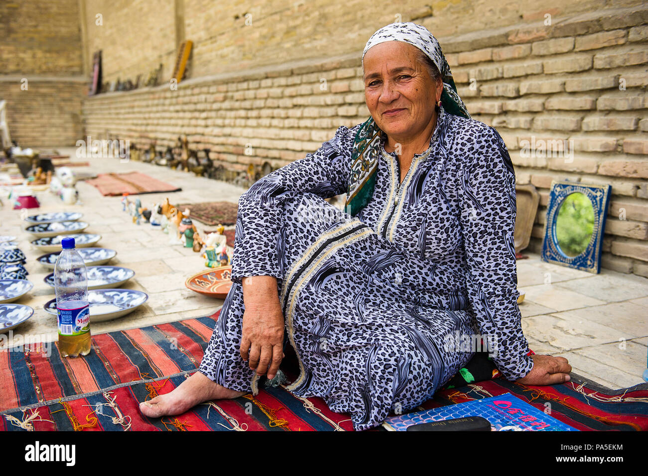 BUKHARA, UZBEKISTAN - JUNE 7, 2011: Unidentified Uzbek woman sells the carpets in Uzbekistan, Jun 7, 2011.  81% of people in Uzbekistan belong to Uzbe Stock Photo