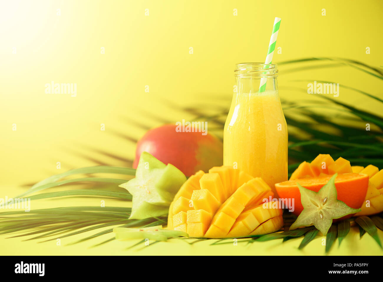 Delicious juicy smoothie with orange fruit and mango on yellow background.  Copy space. Pop art design, creative summer concept. Fresh juice in glass b  Stock Photo - Alamy