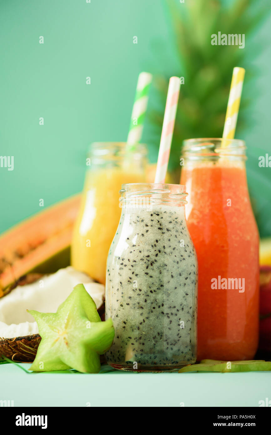 Papaya, dragon fruit, pineapple, mango smoothie in jars on turquoise background. Detox, vegan