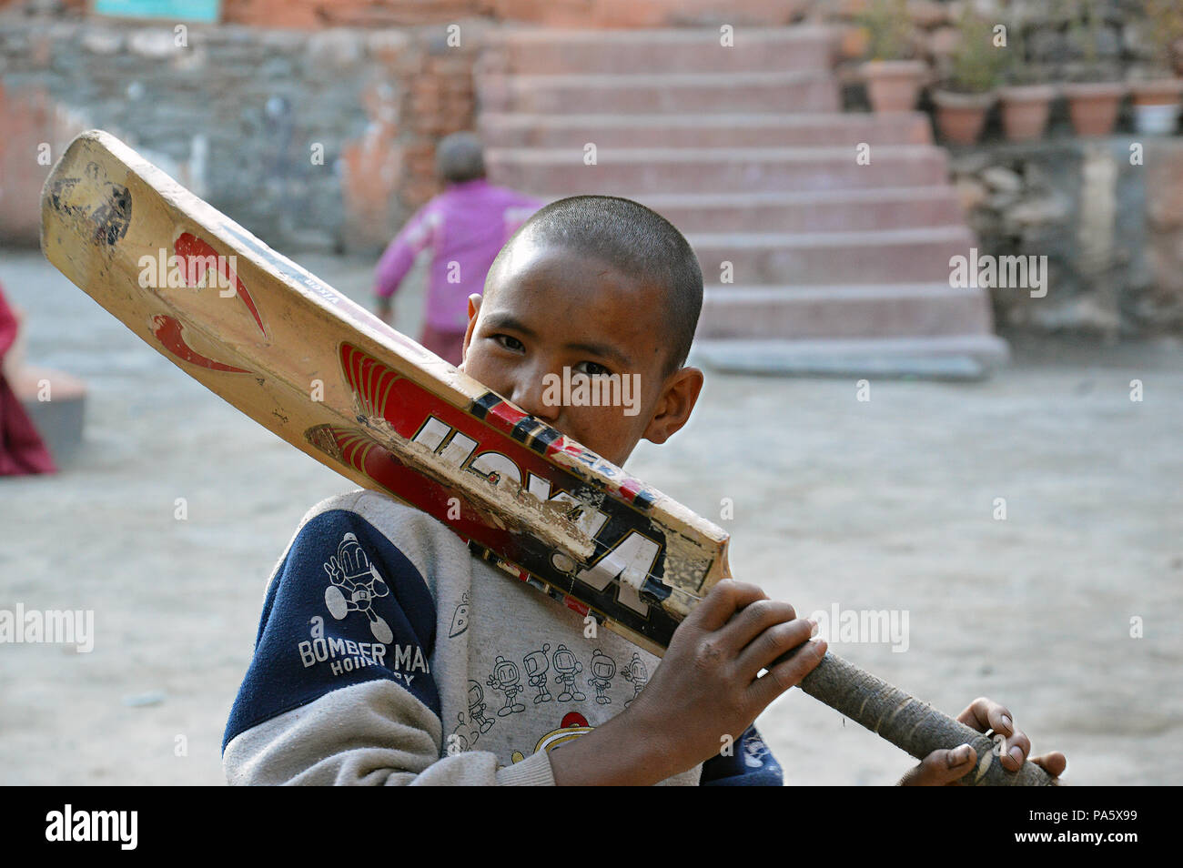 A boy kissing an old cricket bat at a school in Kagbeni, Lower Mustang, Nepal.11.09.2014. Stock Photo