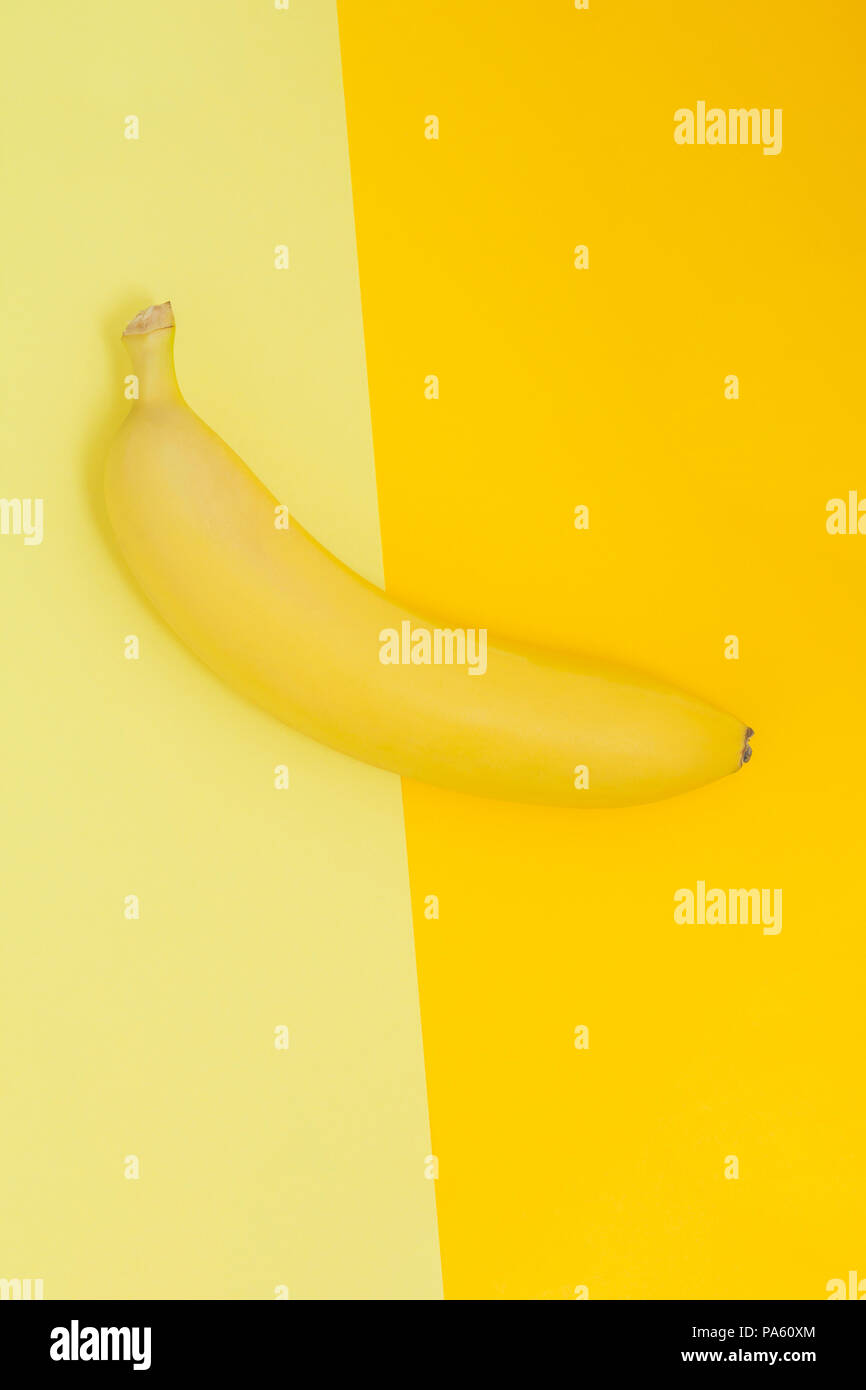 Creative view of a banana on a background of similar colors. Yellow background. Abstraction. Template. Stock Photo