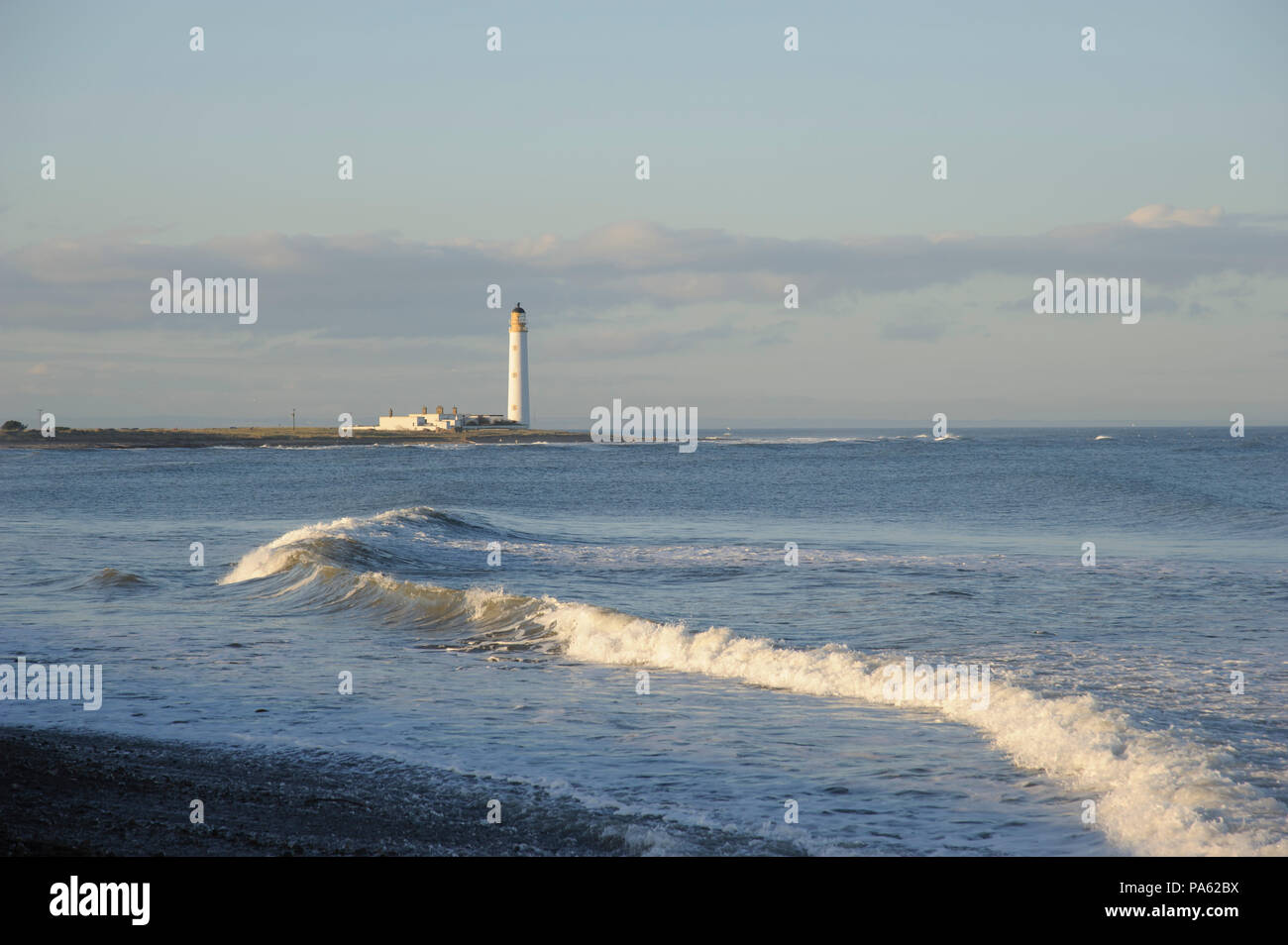 02-12-14. Dunbar, Scotland, UK. Barns Ness lighthouse and a curving wave. Photo © Simon Grosset Stock Photo