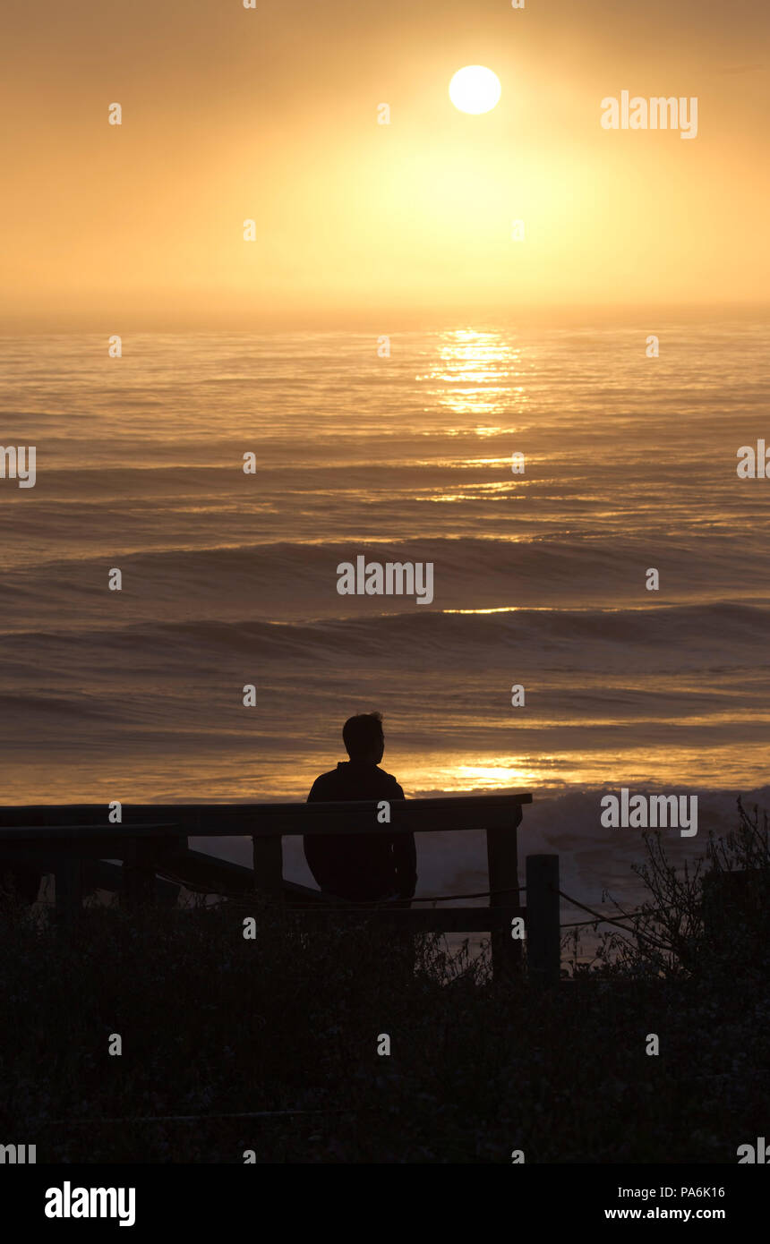 Man Watching the Sunset over Pacific Ocean Stock Photo