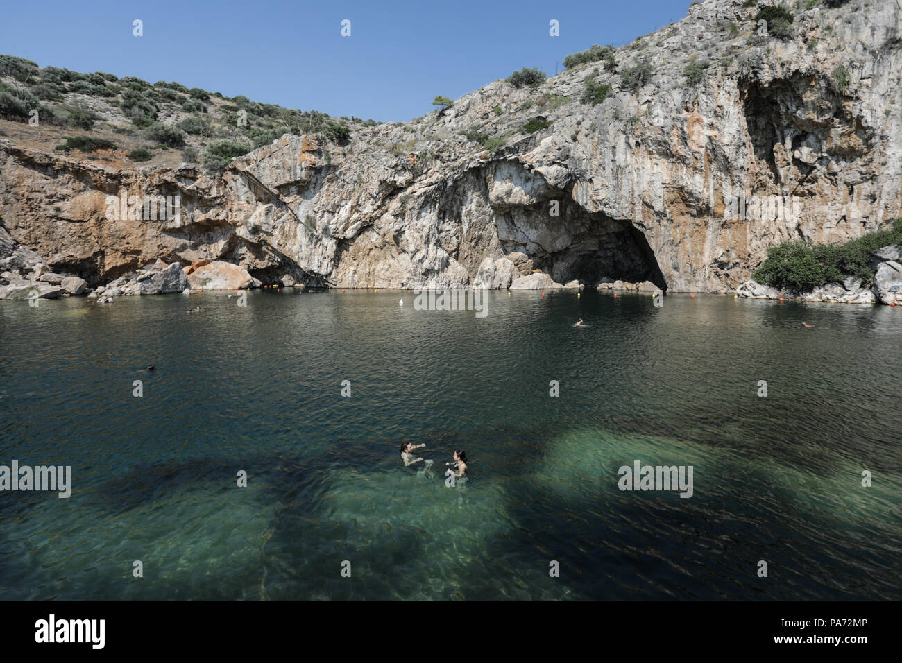 Athens. 19th July, 2018. Photo taken on July 19, 2018 shows people swimming in Vouliagmeni Lake in south region of Athens, Greece. Situated on an idyllic landscape, the rare geological phenomenon of the Vouliagmeni Lake attracts many visitors. Credit: Xinhua /Lefteris Partsalis/Xinhua/Alamy Live News Stock Photo