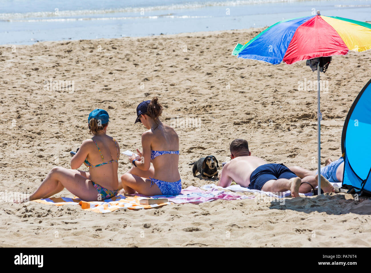 Bournemouth, Dorset, UK. 21st July 2018. UK weather: hot and sunny at Bournemouth beaches, as sunseekers head to the seaside to soak up the sun at the start of the summer holidays. Sunbathing on the beach with dachshund sausage dog. Credit: Carolyn Jenkins/Alamy Live News Stock Photo