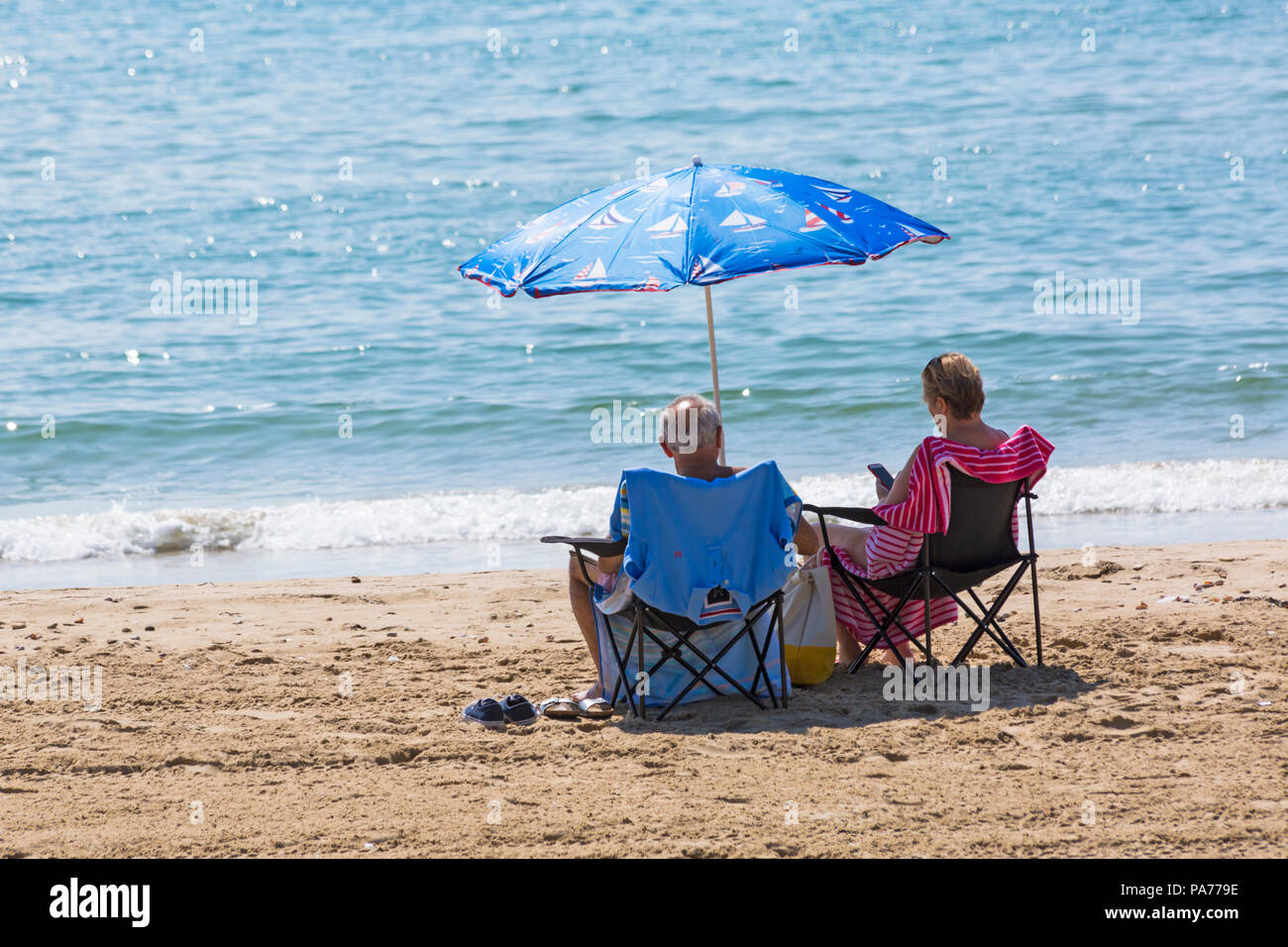 Bournemouth, Dorset, UK. 21st July 2018. UK weather: hot and sunny at Bournemouth beaches, as sunseekers head to the seaside to soak up the sun at the start of the summer holidays. mature couple relaxing in chairs under nautical themed parasol at the seashore on Bournemouth beach. Credit: Carolyn Jenkins/Alamy Live News Stock Photo