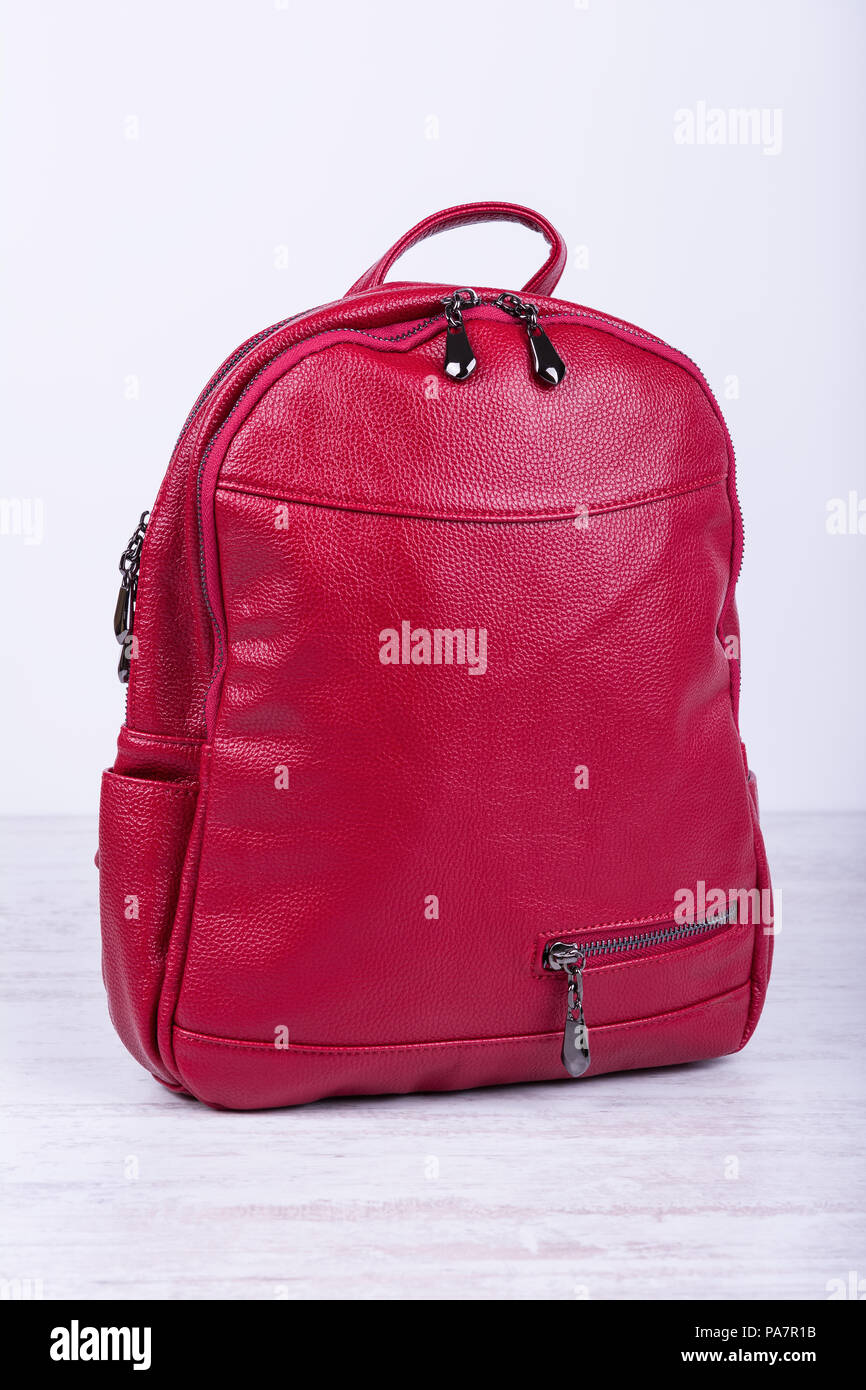 Red leather fashionable female backpack on white wooden background. Stock Photo