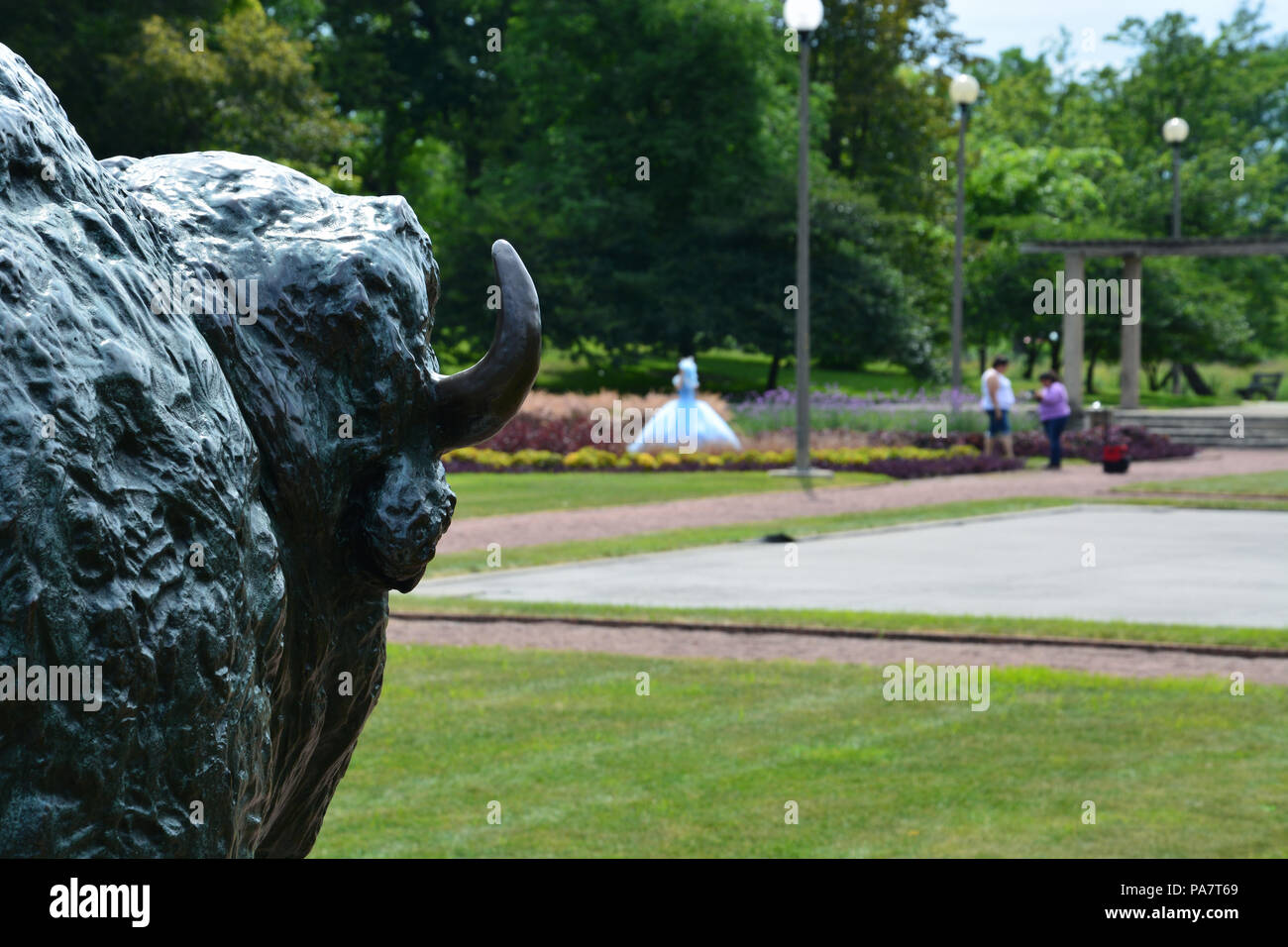 Bison monument looking off towards a family photo shoot in the Humboldt Park formal gardens on Chicago's west side. Stock Photo