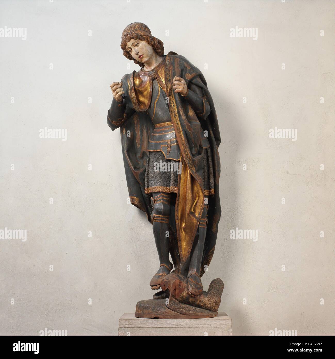 Saint Michael. Culture: Spanish. Dimensions: Overall: 73 1/2 in., 235lb. (186.7 cm, 106.6kg). Date: ca. 1530.  The warrior-archangel Michael, clad in intricately carved and painted armor, treads on a dragon, a symbol of the devil. In his left hand, he carried scales, symbolic of the Last Judgment, to which he summoned earthly souls. Michael's right hand once held a lance, and his wings have been lost. The forward-bending pose and foreshortening indicate that the figure was made to be positioned at a considerable height, perhaps above or flanking the central shrine of a large retable. Museum: M Stock Photo