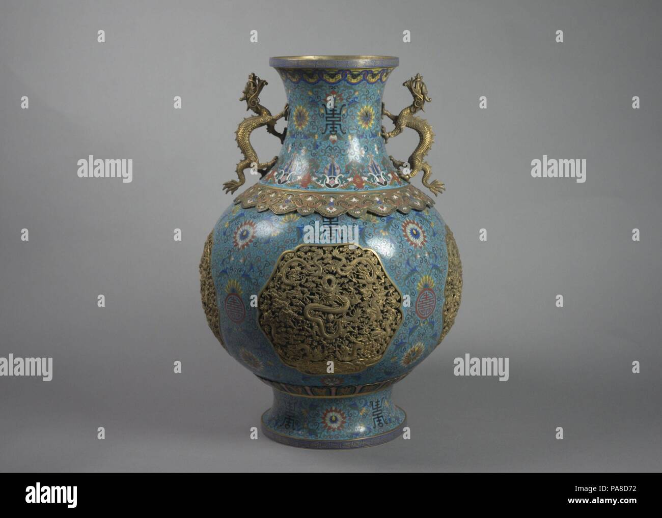One of a Pair of Vases with Dragon Handles. Culture: China. Dimensions: H. 18 1/2 in. (47 cm); Diam. 13 in. (33 cm); Diam. of rim 6 1/4 in. (15.9 cm); Diam. of foot 7 3/8 in. (18.7 cm). Date: 19th century.  Cloisonné is a technique for creating designs on metal whereby enclosures made from copper or bronze wire that has been bent or hammered into a desired pattern are filled with colored glass paste. Known as cloisons (French for 'partitions'), the enclosures are generally pasted or soldered onto the metal body. The glass paste, or enamel, is colored with metallic oxide and painted into the co Stock Photo